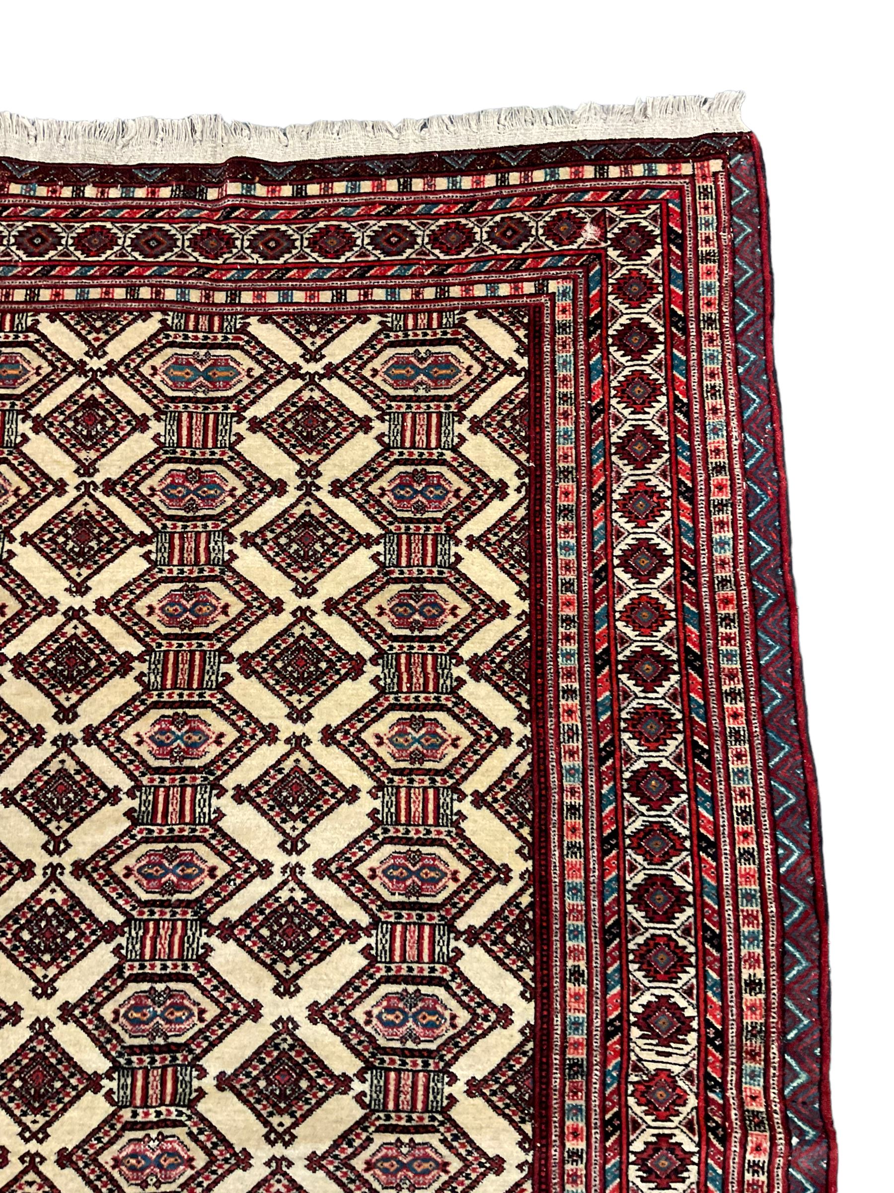 North East Persian Turkoman rug, ivory ground field decorated with repeating Gul motifs, multi-band border decorated with geometric patterns and motifs