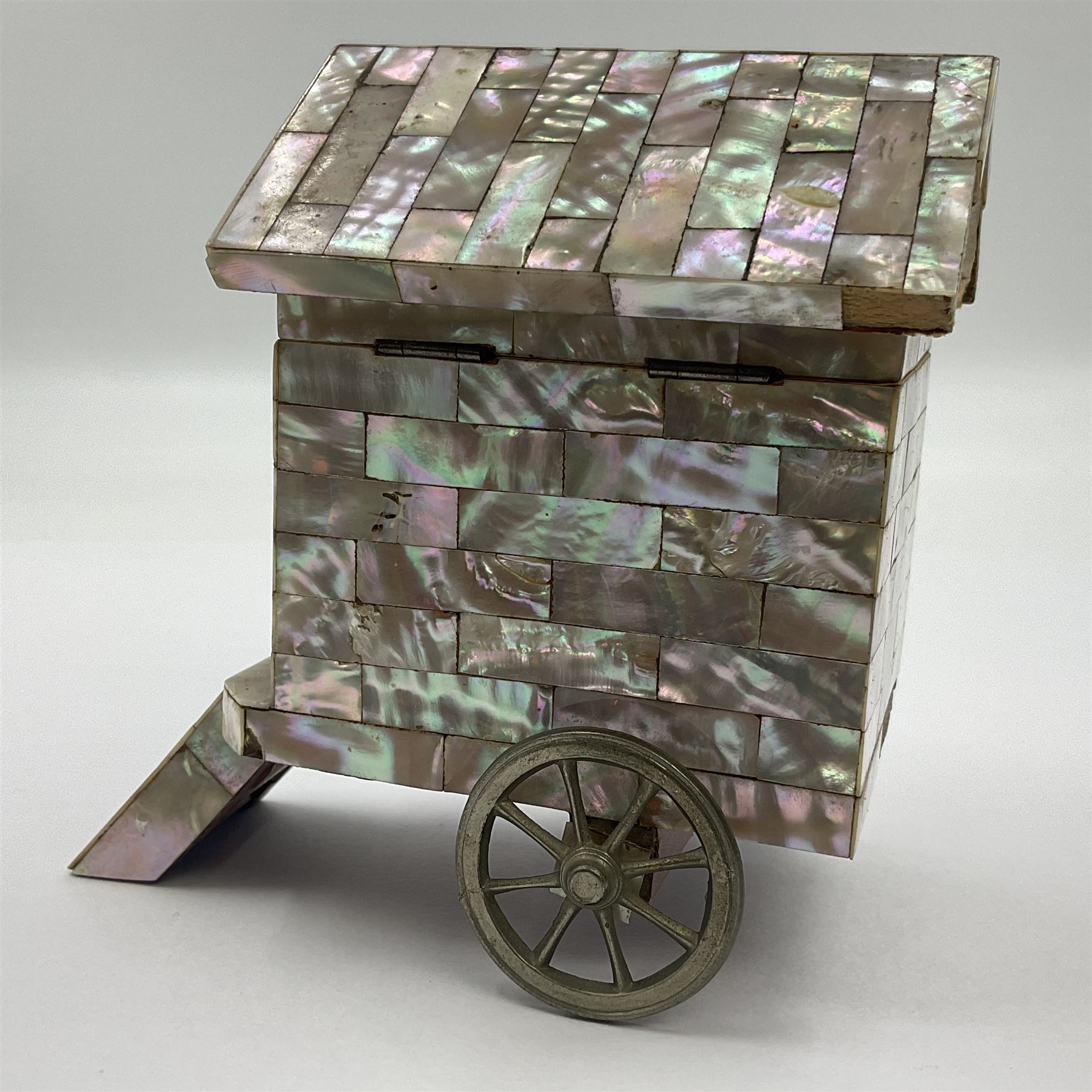 19th century French souvenir jewellery casket in the form of a bathing machine, having mother of pearl panelled tiled effect body, hinged roof/cover revealing a blue silk fitted interior with cushioned base, two silvered metal wheels, abalone shell door and mother of pearl steps, inscribed 'Berck Plage' in blue, H12cm, W13cm 