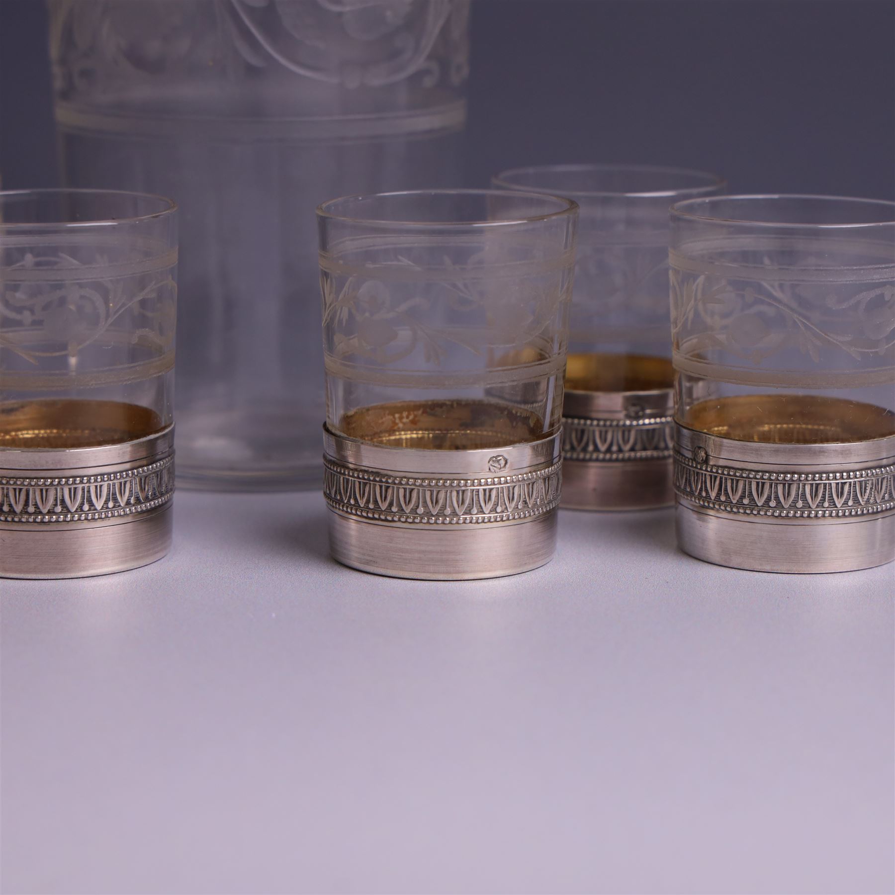 French silver mounted glass decanter and shot glass set, the decanter with silver covered stopper, removable silver collar, and etched decoration to glass body, the six silver mounted glasses each with etched decoration, silver stamped with Minerva's head, decanter H 21cm