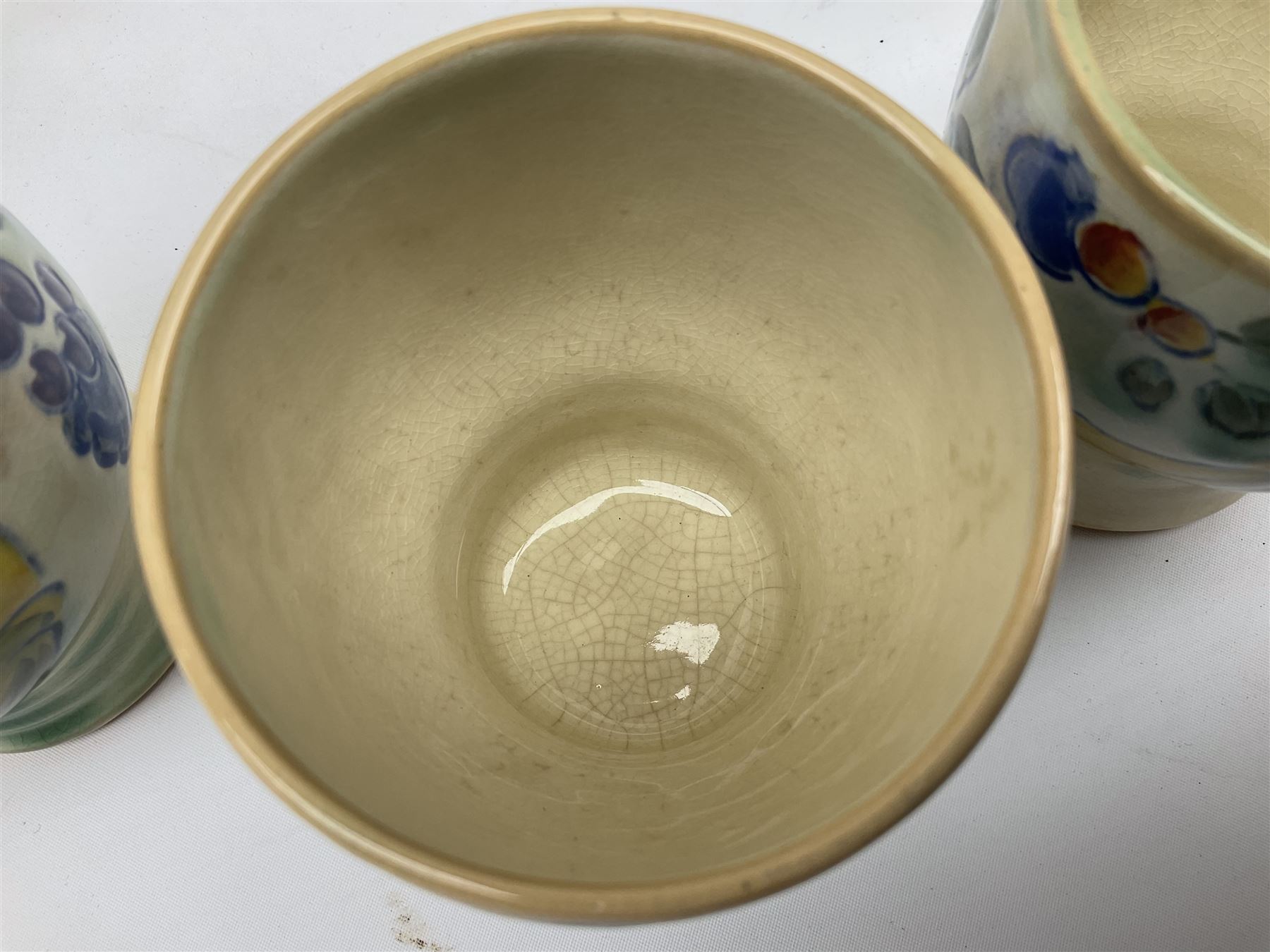 Early 20th century Royal Doulton Brangwyn Ware jug and set of six beakers, designed by Frank Brangwyn RA, all decorated in the Harvest pattern with stylised leaves and fruit on mottled peach and green ground, all with printed marks beneath, date code for 1920s, largest H18cm