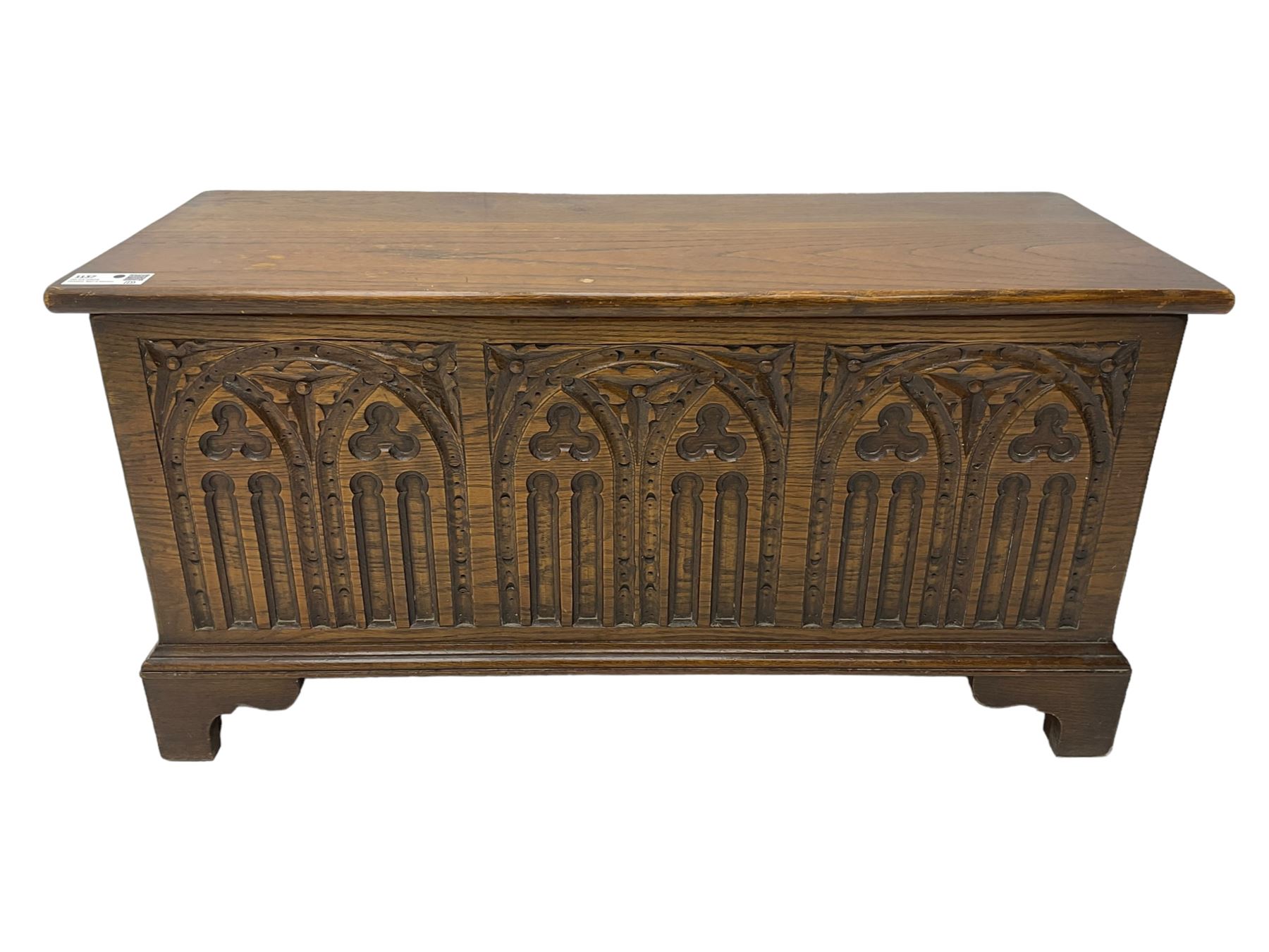 Mid-20th century oak blanket box, hinged lid over front carved with Gothic tracery work and flower heads, on bracket feet