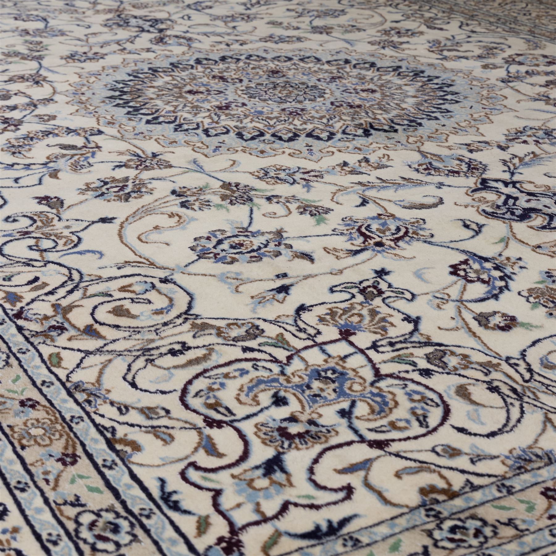 Central Persian Nain hand-knotted carpet, wool with silk highlights, ivory field with central radiating medallion surround by an intricate arrangement of scrolling vines and floral motifs, within conforming spandrels and matching border, cotton fringe ends 