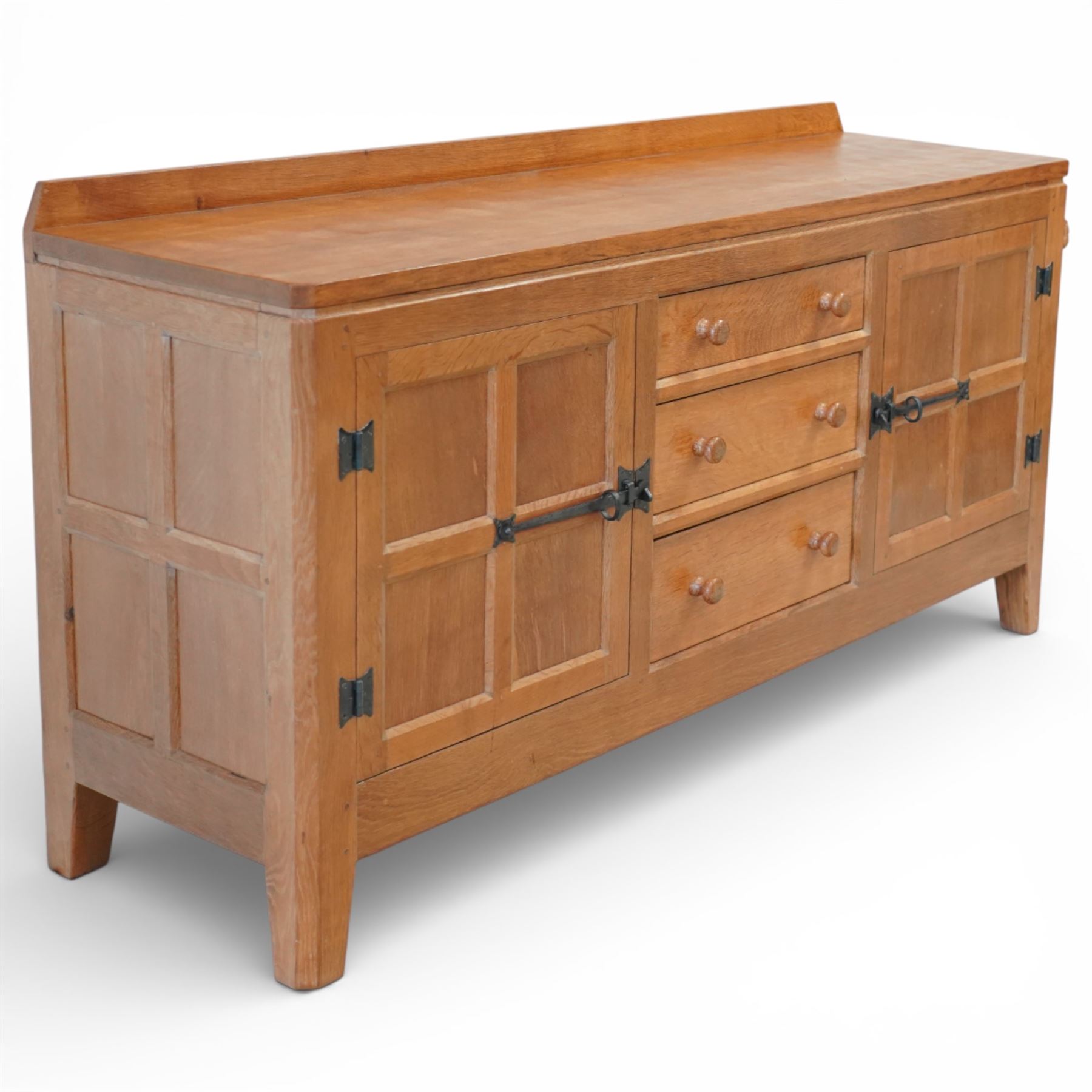 Rabbitman - oak sideboard adzed top with galleried top, with three graduating drawers to the centre, flanked by two panelled and lightly adzed doors, iron latches and hinges, raised on tapered stile supports, with carved rabbit signature, by Peter Heap of Wetwang   