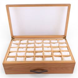 Large wooden watch display case, with glazed lid and spaces for thirty five watches, with drawer beneath containing a collection of leather, metal and other watch straps