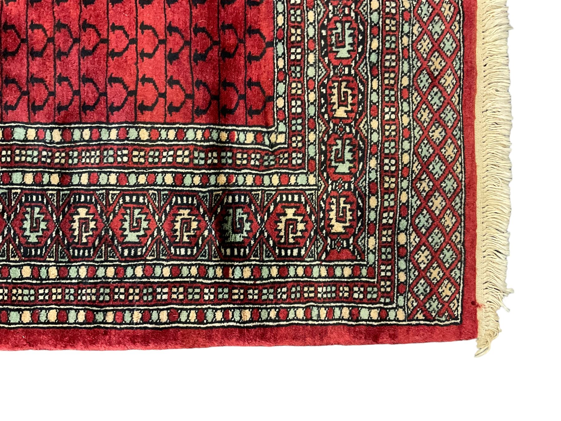Tekke Ensi crimson ground rug, the quartered field decorated with candelabra motifs, multi-guarded border with repeating geometric hexagonal lozenges in blue and ivory