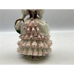 20th century Dresden lace figure, depicting a lady wearing an elaborate lace crinoline dress, carrying a basket of flowers on her arms and in a crinoline hat, with printed mark beneath, H20cm