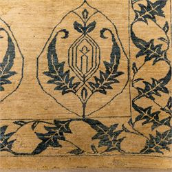Late 20th century Turkish hand-woven carpet, golden beige field decorated with a repeating lattice of stylized medallions enclosing boteh and angular foliate motifs linked by issuing scrolling vinery within a border of complementary stylized leaf scrolls