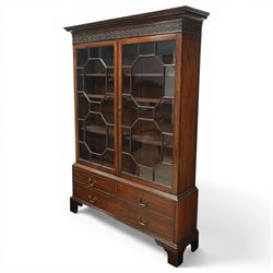 Early 20th century mahogany glazed bookcase, the moulded cornice above a carved frieze with interlaced ornament, enclosed by a pair of astragal glazed doors with geometric glazing bars, the base fitted with two short over two long drawers with brass swan neck handles, raised on bracket feet