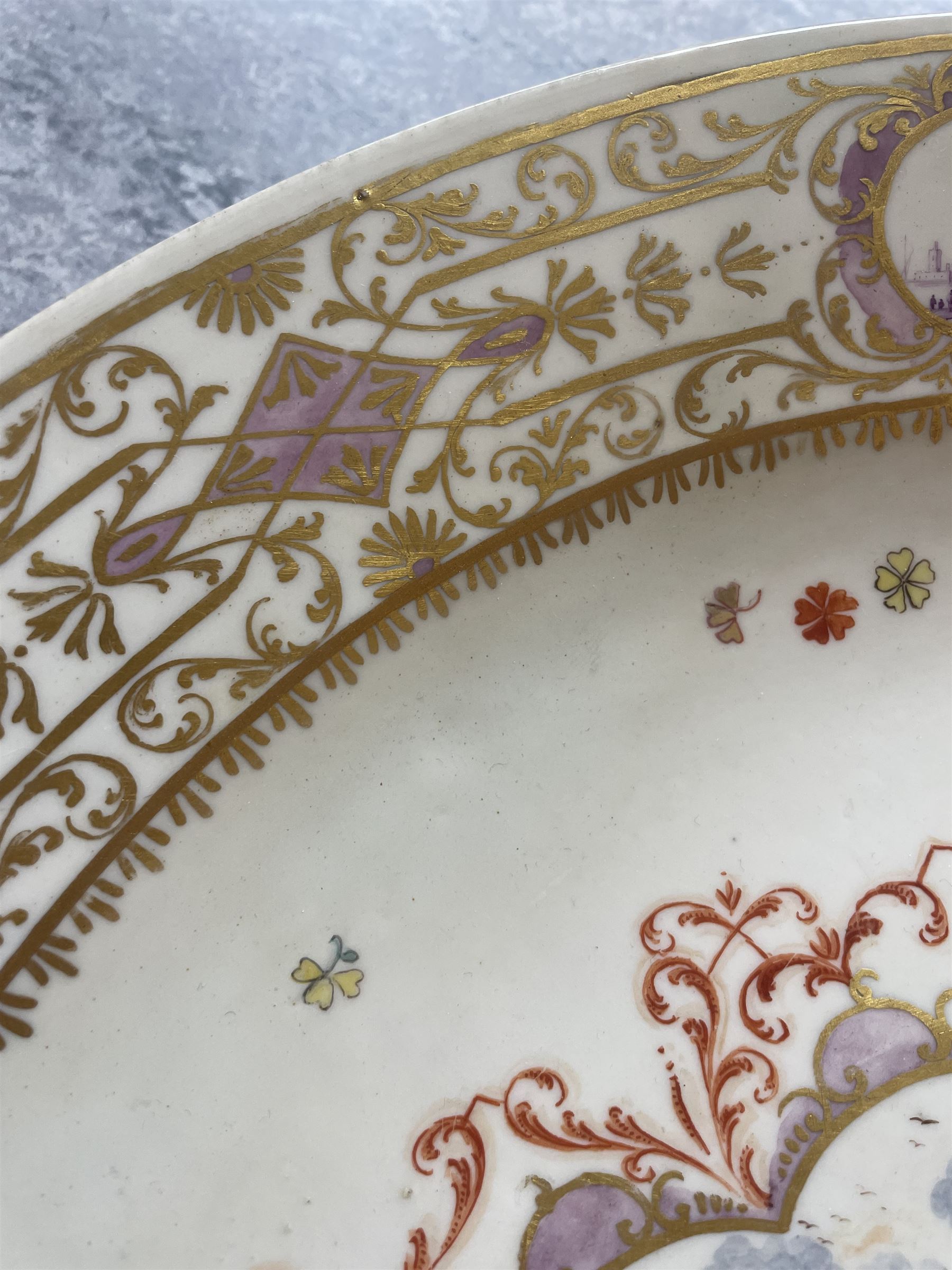 Large and impressive 18th century Meissen dish, finely painted with a chinoiserie scene to a central shaped reserve, depicting figures and attendants engaged in various pursuits, the reserve with gilt scrollwork edge, filled with Böttger lustre and detailed with iron red scrollwork, surrounded by flower heads, the rim with four quatrofoil Kauffahrtei scene panels of merchants and figures by a quayside in purple monochrome, with gilt scroll border, with under glazed blue crossed swords mark, and gilt gilders mark, D39cm
