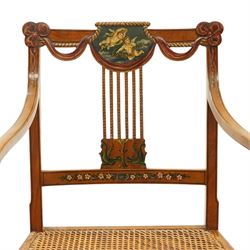 Late 19th century Adam Revival painted and parcel-ebonised satinwood open armchair, the cresting rail centred by a painted panel depicting putti holding garlands, within draped swag ornament and moulded ribbon-twists, over a pierced vertical splat with gilt beaded detail, the downswept arms and caned seat above a painted lattice and floral frieze, raised on ring-turned tapering front supports with musical instrument painted panel and acanthus leaves