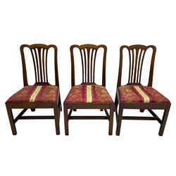 Set of six (5+1) George III mahogany dining chairs, shaped cresting rail over pierced and flared splat, drop-in seat upholstered in crimson and ivory floral patterned fabric, raised on chamfered square supports united by H-stretcher