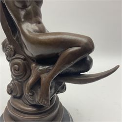 Bronze figure modelled as a nude female figure seated on a crescent moon, upon a stepped circular base, H29cm 