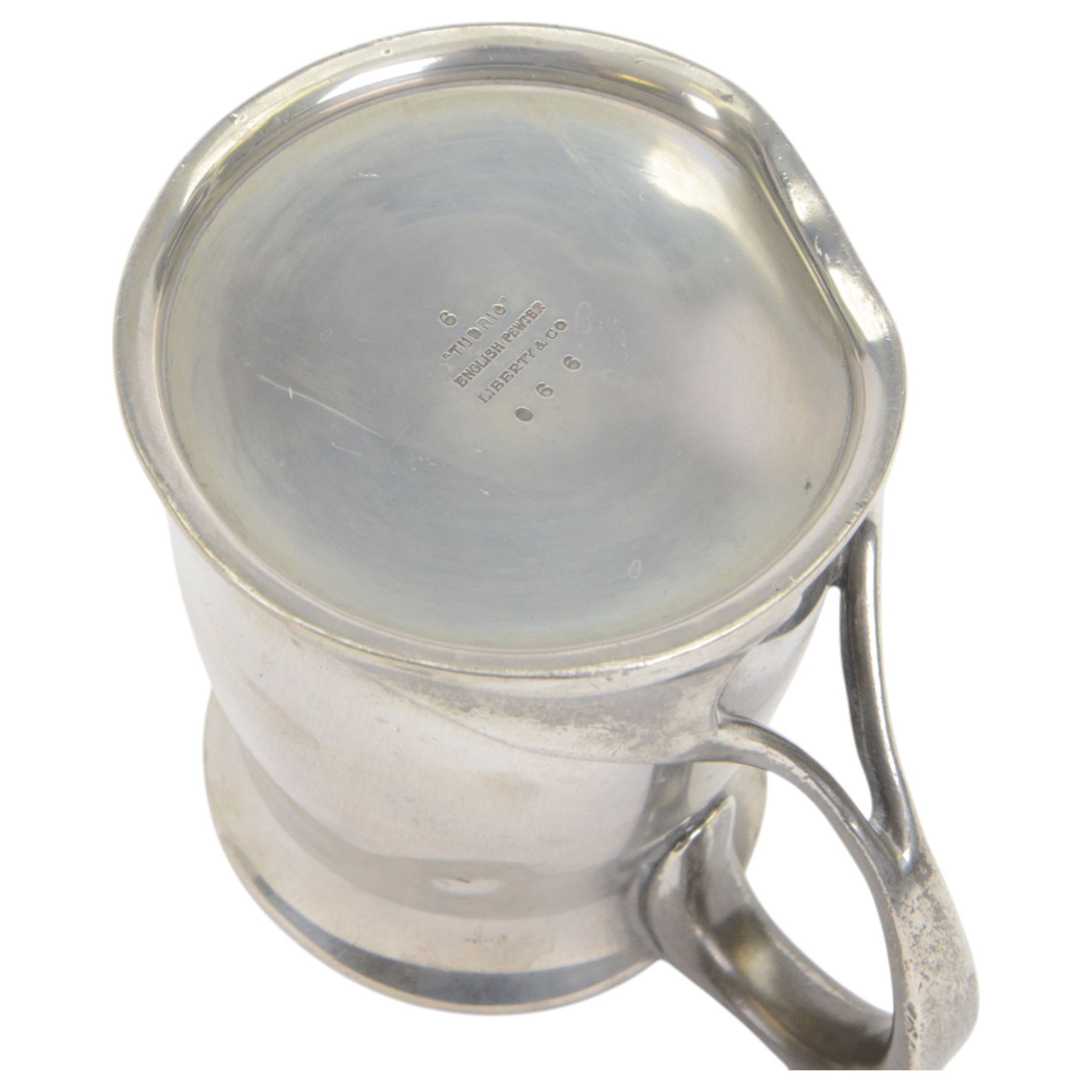 Liberty & Co Tudric pewter tankard, designed by Oliver Baker, model No.066, with a flared rim and whiplash scroll handle, stamped beneath Tudric English pewter, Libery & Co 066
