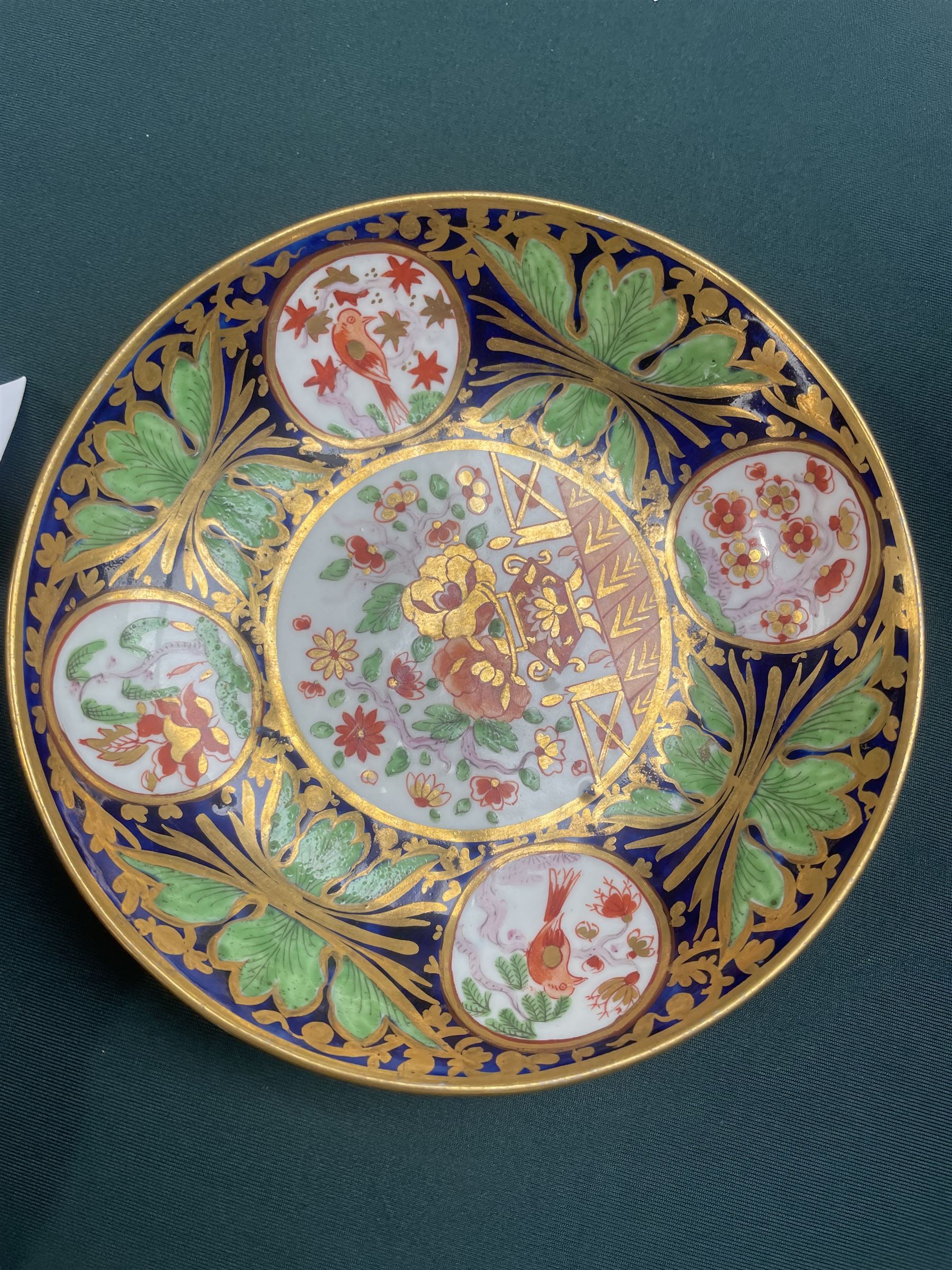19th century teacup and saucer, possibly Coalport, decorated with panels of flowers on a cobalt blue ground with gilt decoration; together with two other teacup and saucer pairs, one with hand painted landscape decoration 