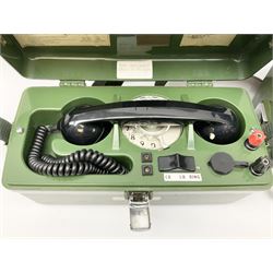 Three field telephones, with rotary dials, in hard plastic cases, one missing its cover, all with canvas straps, together with an extra handset. 