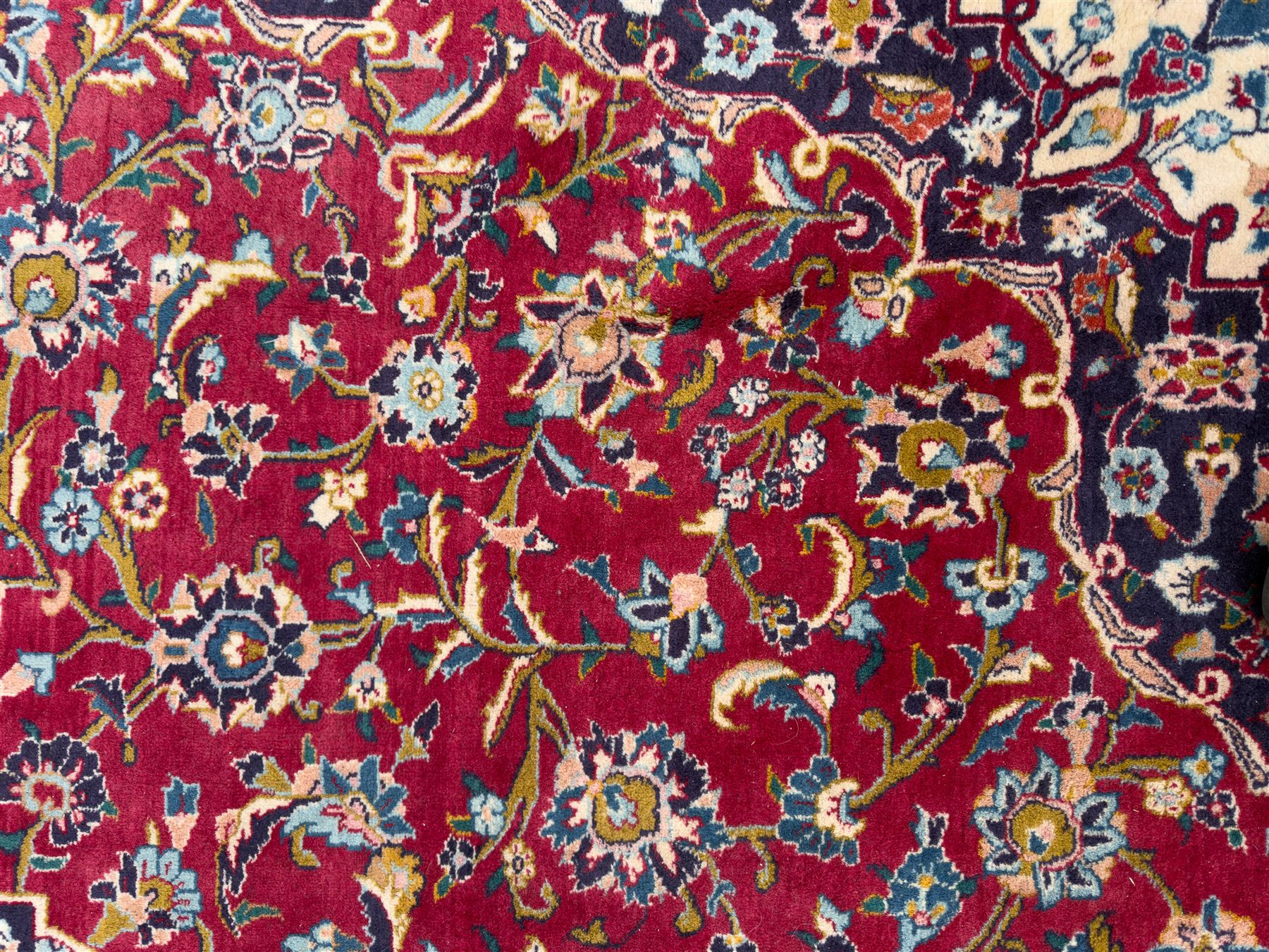 Pair of Persian wool rugs, each with rich red ground, one centred with a diamond-shaped medallion and navy spandrels within a floral field, the other with radiating floral medallion and scrolling foliate motifs, both enclosed by multiple borders with palmette and flowerhead designs, from the region of Kashan 291x376, 299 x 378 
