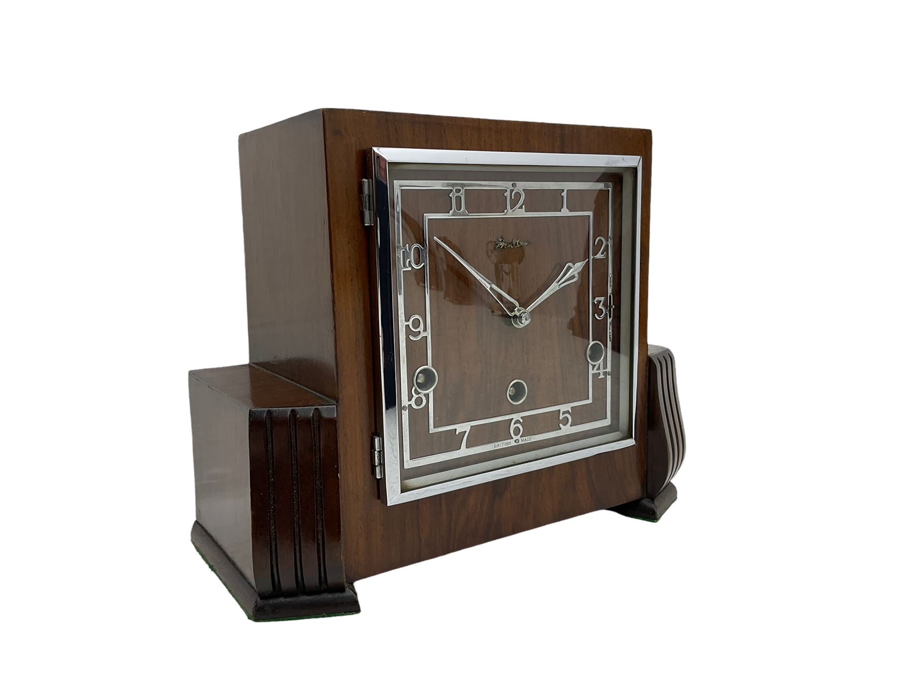  A  1930s “Bentima” Westminster chiming English art deco mantle clock in a stylised mahogany case with a square dial, chrome Arabic numerals and corresponding pierced hands within a chrome bezel, three train Perivale movement chiming the quarters on 4 gong rods, strike/silent facility. With pendulum and key. H24 



