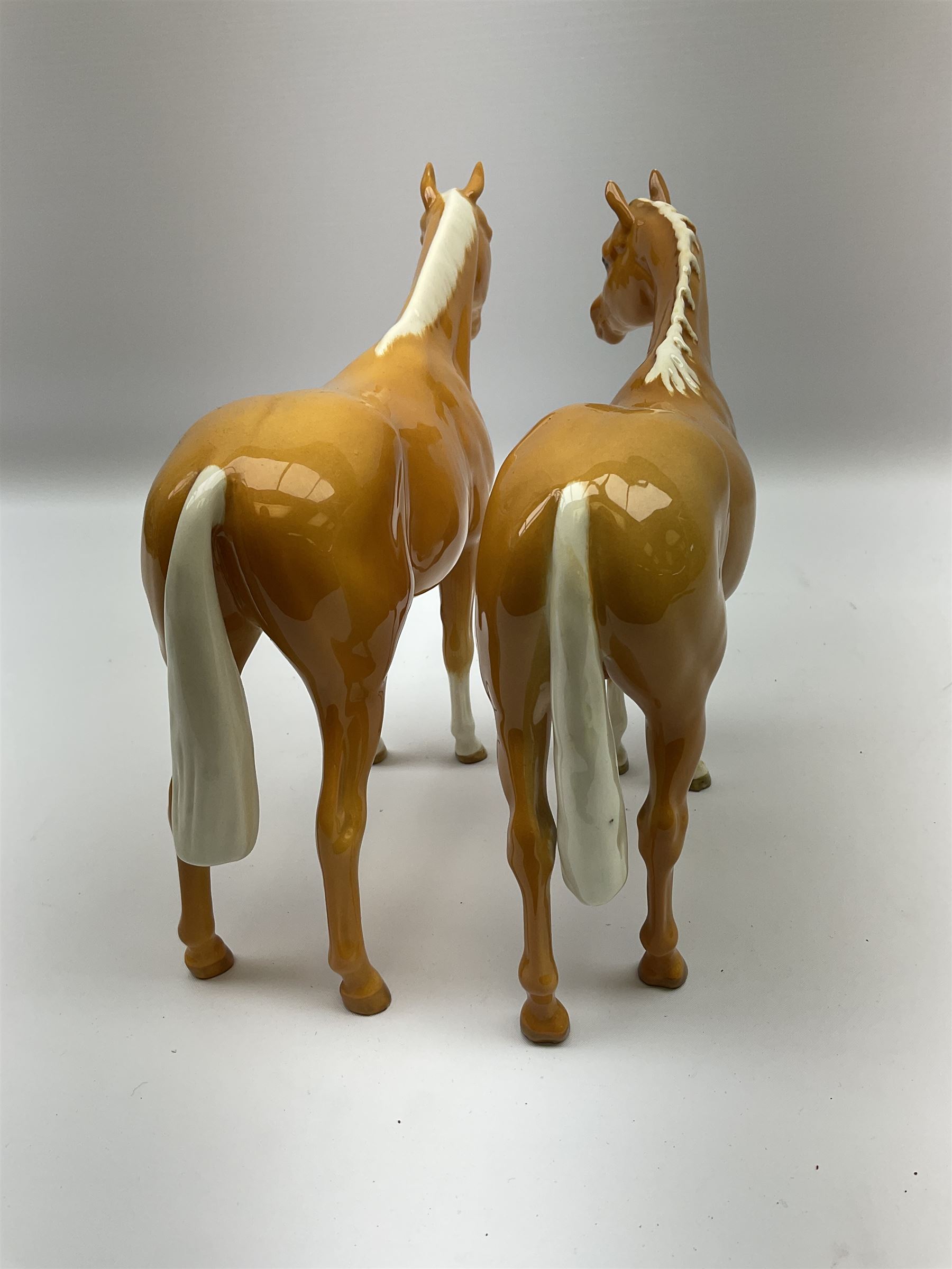 Two Beswick Palomino horse figures, comprising 'Imperial' Palomino, model no. 1557, designed by Albert Hallam and James Hayward, together with Palomino Arab model no. 1771, both stamped, tallest H20cm