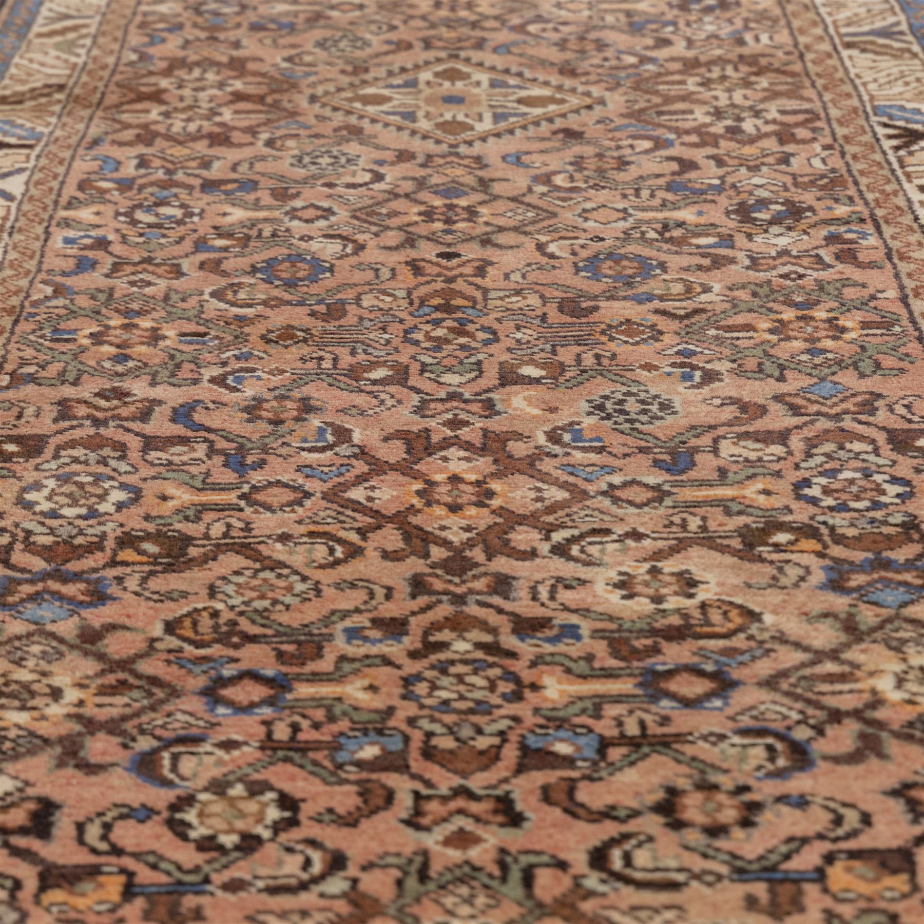North West Persian Malayer hand-knotted runner, camel pink field decorated with an all-over lattice of Herati design, composed of rosettes and enclosed by angular leaves and stylized fish motifs, principal border of ivory ground decorated with stylized angular vine scroll and geometric palmettes, flanked by narrow guard stripes, with cotton fringe ends 