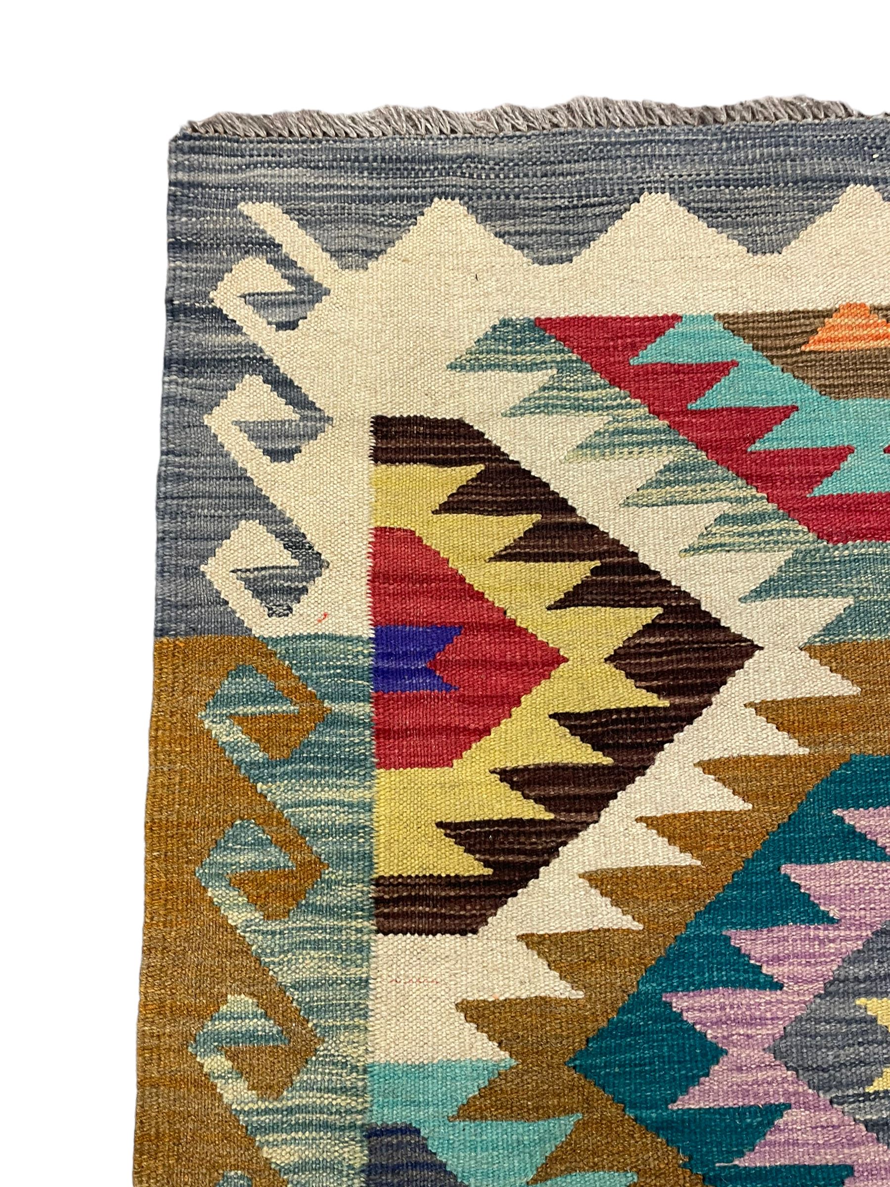 Anatolian Turkish Kilim rug, multi-coloured ground, decorated with geometric stepped lozenges with in a scrolled border