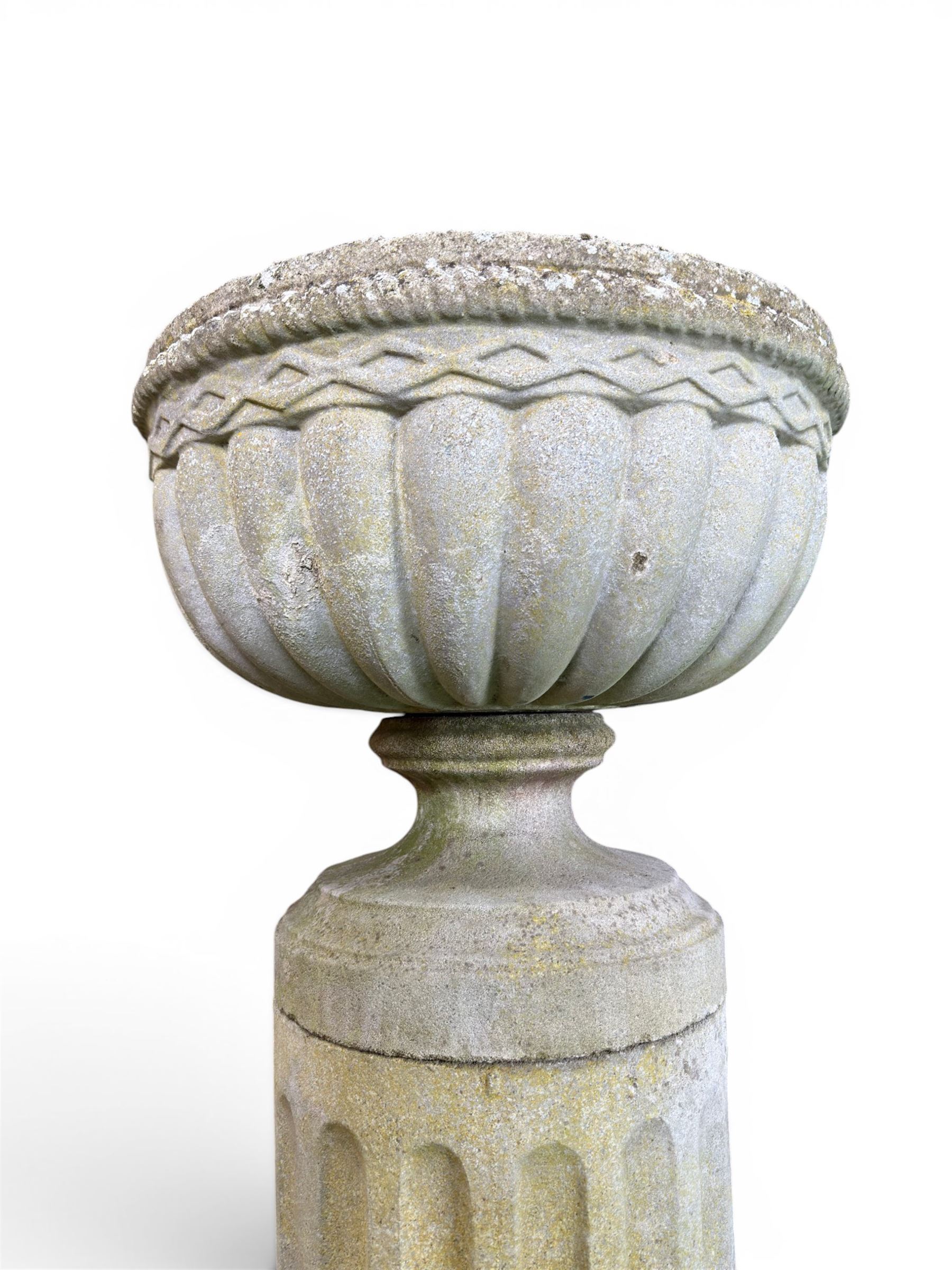 Four 20th century good quality weathered cast stone pedestal urns, circular lobed bowls with rope twist and lattice border, raised on squat base with fluted columns