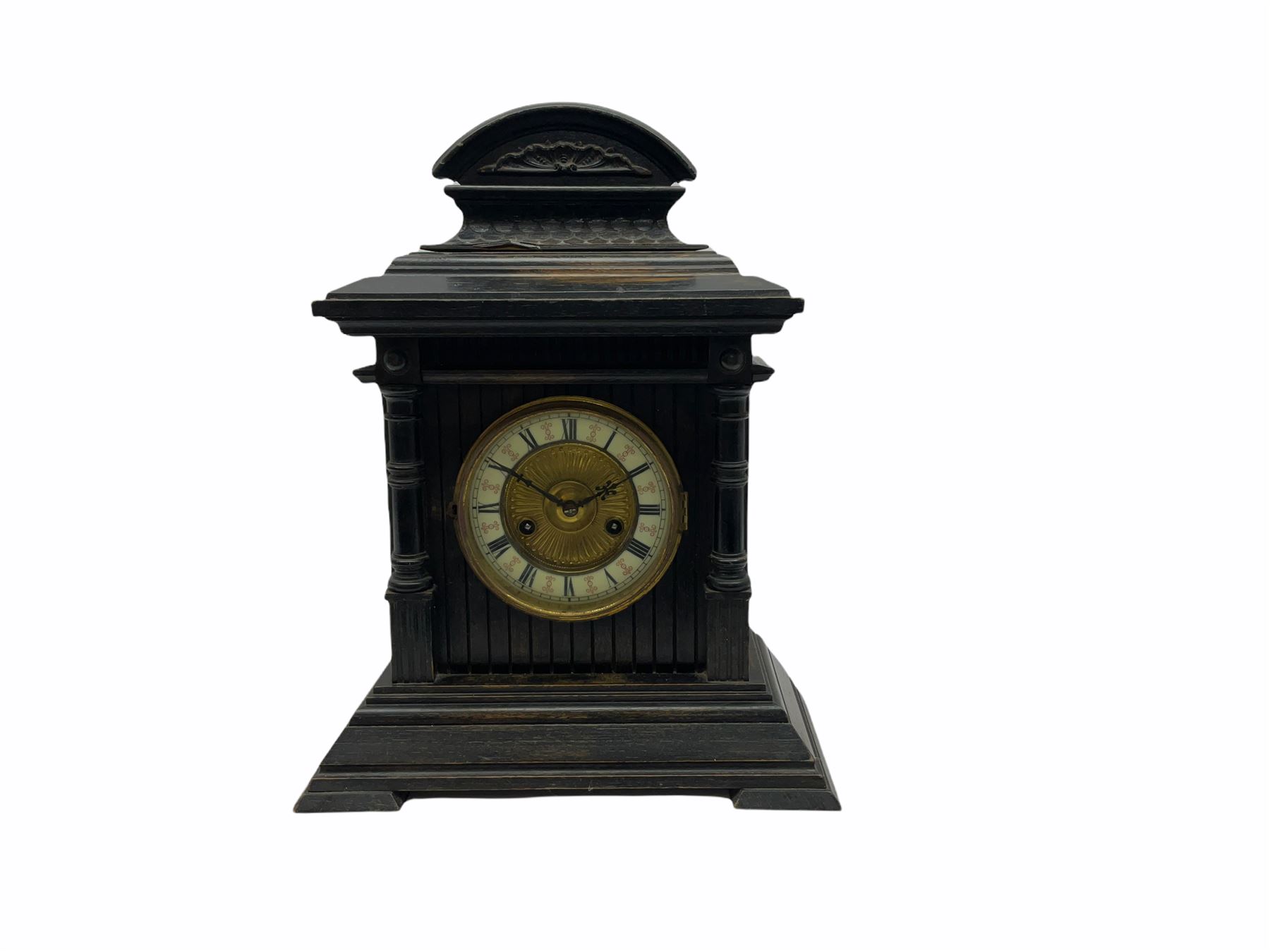 An early 20th century fourteen-day German mantle clock in a wooden case striking the hours on a coiled gong, two-part dial with a gilt centre, ivorine chapter ring with roman numerals, minute track and half-hour markers, steel Fleur de Lys hands and brass spun bezel, case on a splayed stepped plinth with cluster columns, wide cornice and carved broken arch pediment, original Hamburg American Clock Company (HAC) trade labels attached inside the case door.