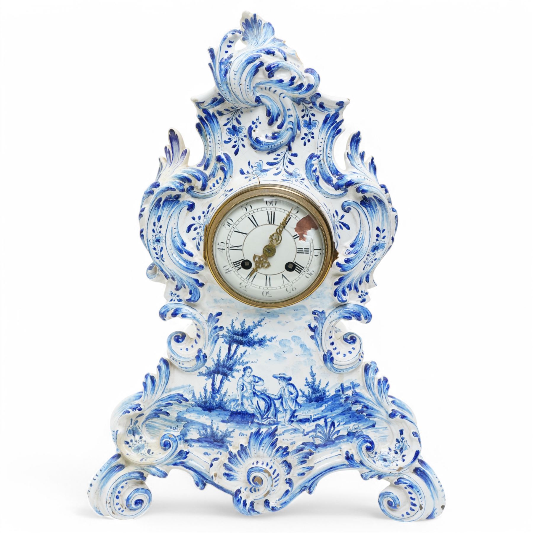 19th century delft blue and white Rococo style 8-day mantle clock, with a scrolling case and floral decoration, depiction of a courting couple in 18th century dress to the front and a contrasting scene of sailing ships on a lake to the rear, with a late 19th-century French twin train movement, enamel dial with Roman numerals, five minute Arabic's and gilt Louis XVI hands within a glazed cast bezel, with a rack striking movement sounding the hours and half-hours on a bell. No pendulum or key.  