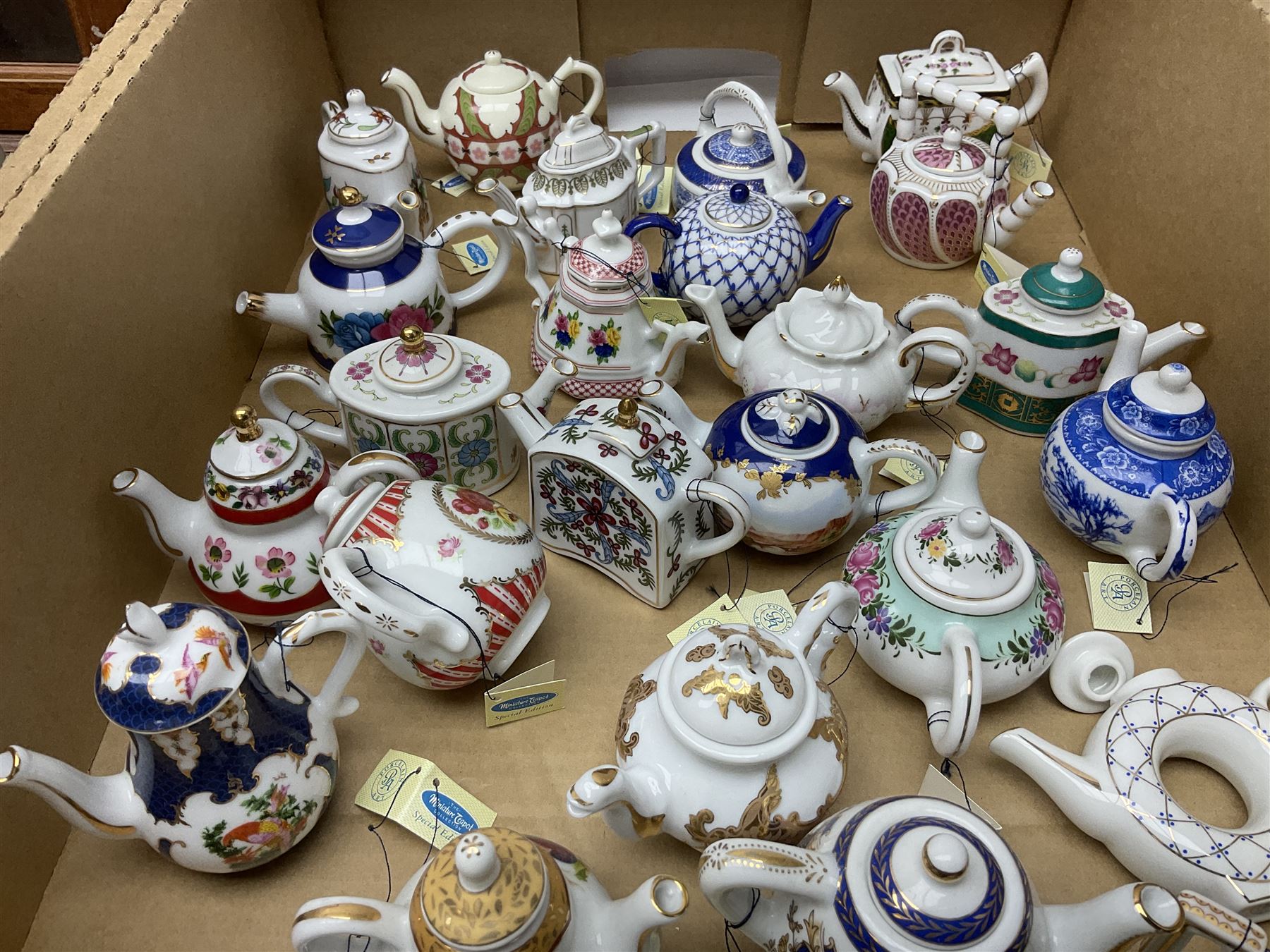 Twenty seven Porcelain Art miniature teapots, with wooden display together with a collection of other ceramics and glassware etc, including Goebel Hummel collectors plates, in three boxes,