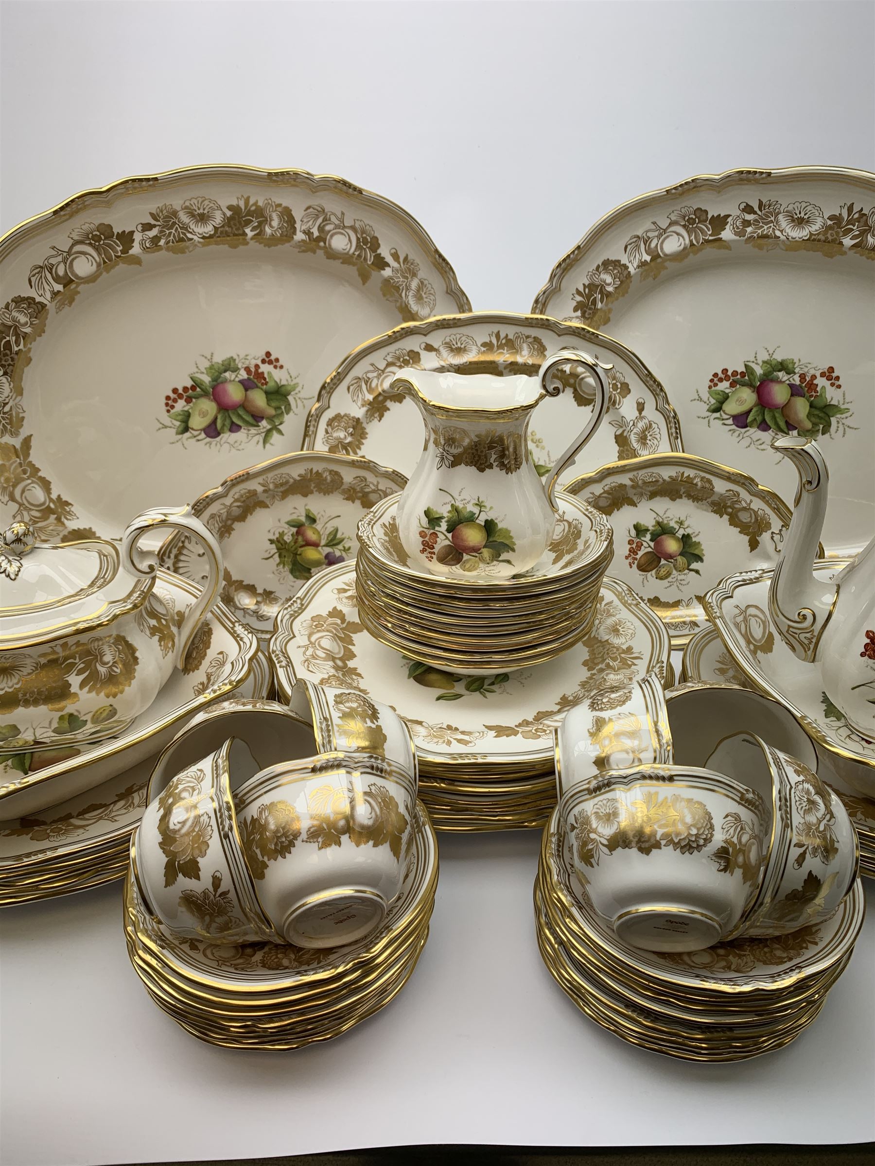 Extensive Spode dinner and tea service, decorated in the Golden Valley pattern, comprising eighteen dinner plates, ten salad plates, ten side plates, ten twin handled soup bowls and ten saucers, ten bowls, two sauce boats and two stands, two square serving dishes, smaller oval serving dish, two tureens and covers, two large oval serving platters, one smaller example, teapot, coffee pot, milk jug, twin handled lidded sucrier, and ten teacups and ten saucers, with red printed marks beneath 