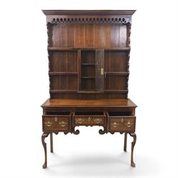 Late 19th century inlaid oak dresser and plate rack, plate rack with projecting cornice and fretwork, with three shaped shelves for plates, central cupboard with inlaid shell and border, brass escutcheon and key, the lower section with crossabanded top, above three drawers with brass handles and inlaid border, shaped apron raised on cabriole supports 