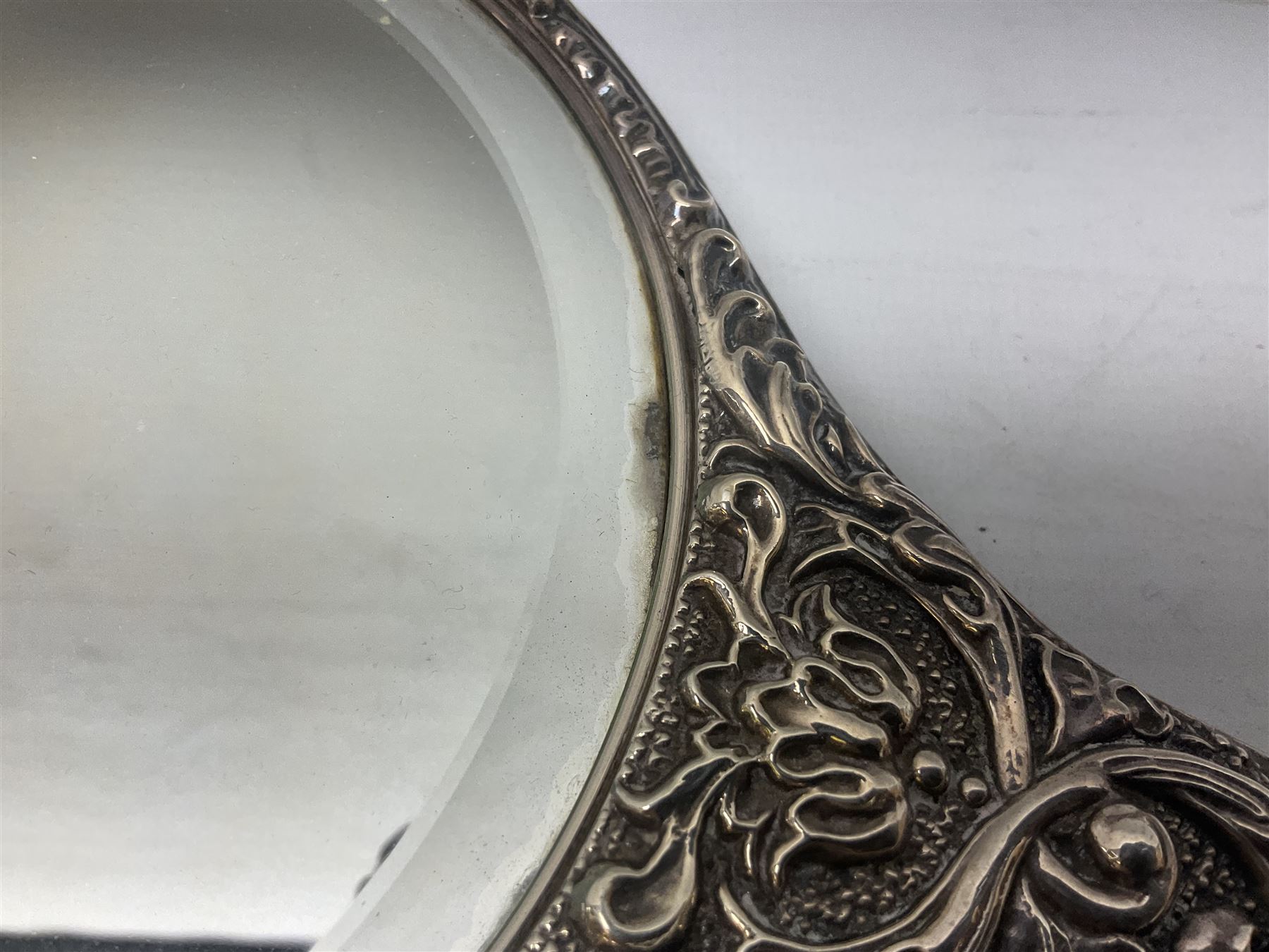 Silver mounted dressing table mirror, embossed with birds, masks, and foliate and C scrolls, hallmarked Birmingham, and fruit knife with mother of pearl handle and silver blade, (2)