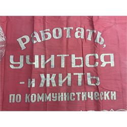 1970s Soviet banner printed in gold on a red ground, roughly translates as 'Transferable Banner - To the winner in the Socialist Competition' and 'Work Study Live by Communism' verso; wreath of wheat ears to either side; tassels on three sides 110 x 155cm