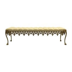 Gilt cast metal window seat bench, rectangular cushioned seat upholstered in buttoned pale gold fabric, ornate foliate cast base on cabriole supports