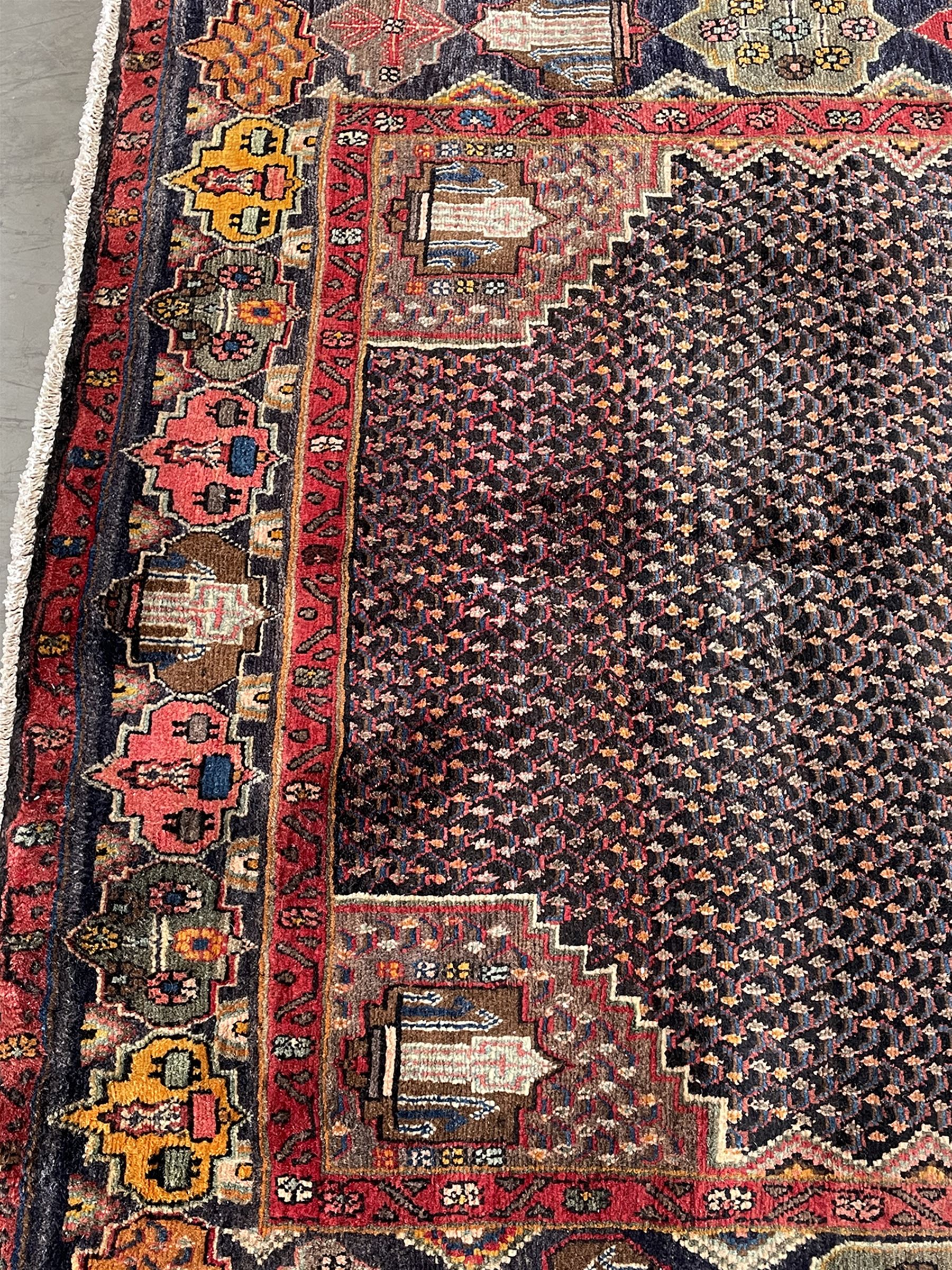 Persian Hamadan blue ground rug, medallion on field decorated with repeating motifs, the guarded border with multiple medallions decorated with flower heads and stylised motifs