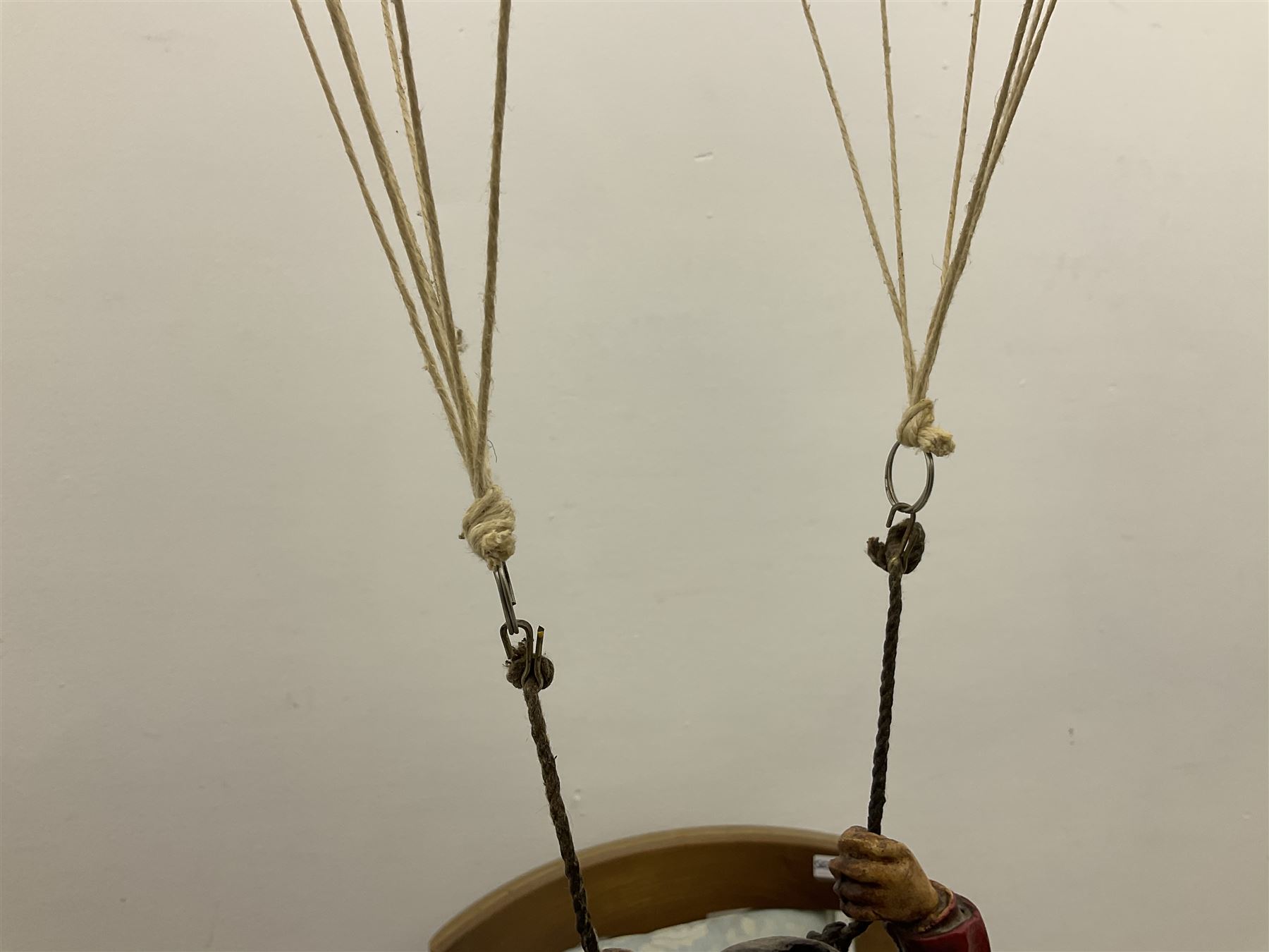 Painted wooden hanging model of a hot air balloon group, the balloon above a wicker basket complete with sandbags and figures, together with a similar example with a clown figure below, H68cm