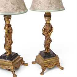Pair of brass table lamps, the central column modeled as a putti upon a square marble base raised upon four claw feet, H29cm