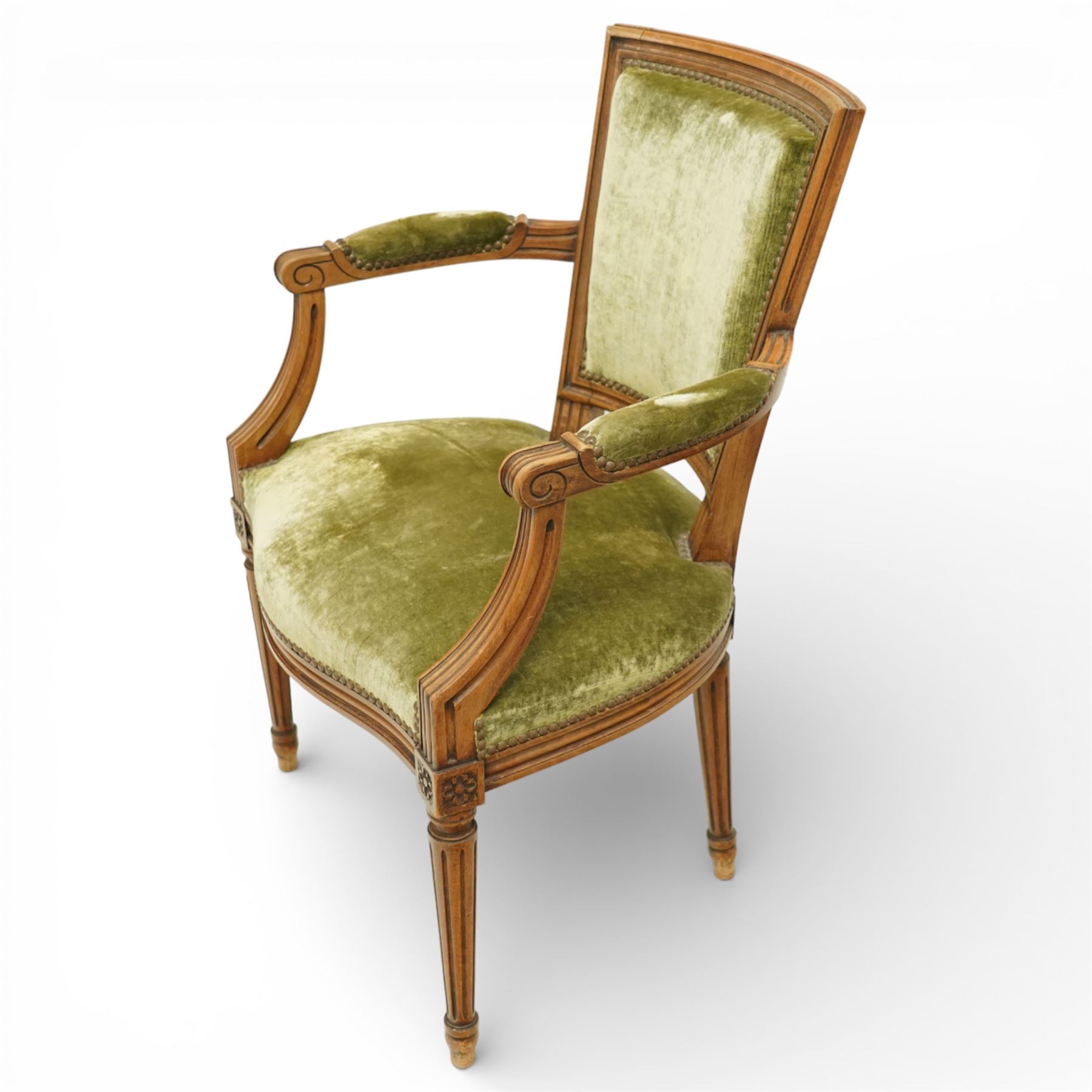 French Louis XVI style walnut armchairs, rectangular upholstered backs with nailhead trim, padded seats upholstered en suite, out-swept arms with upholstered pads, fluted supports with carved rosettes to the knees, on turned and fluted tapering legs