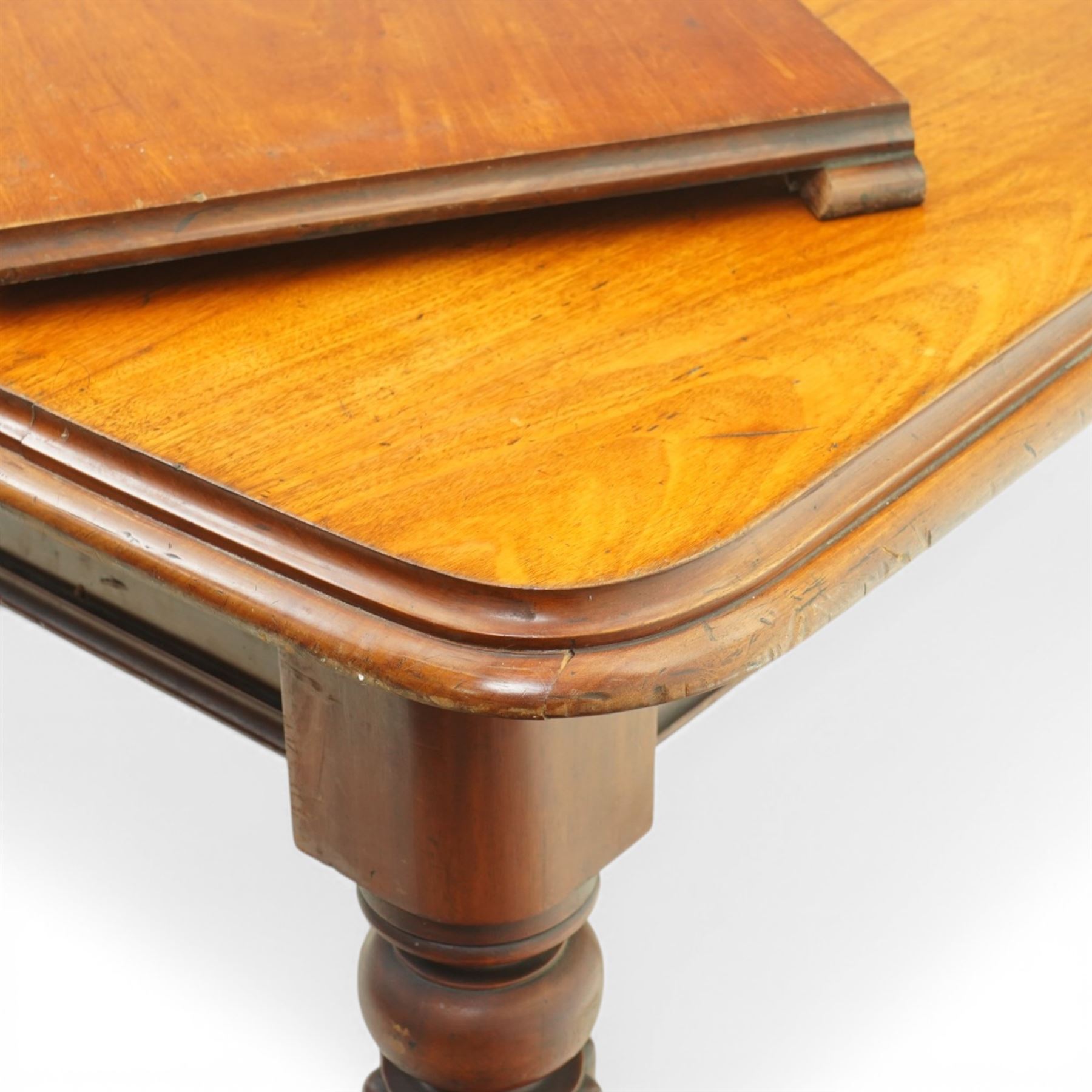 Victorian mahogany extending dining table, rounded rectangular top with moulded edge and two additional leaves, on four turned and fluted supports with brass caps and castors, extension mechanism beneath, in need of restoration