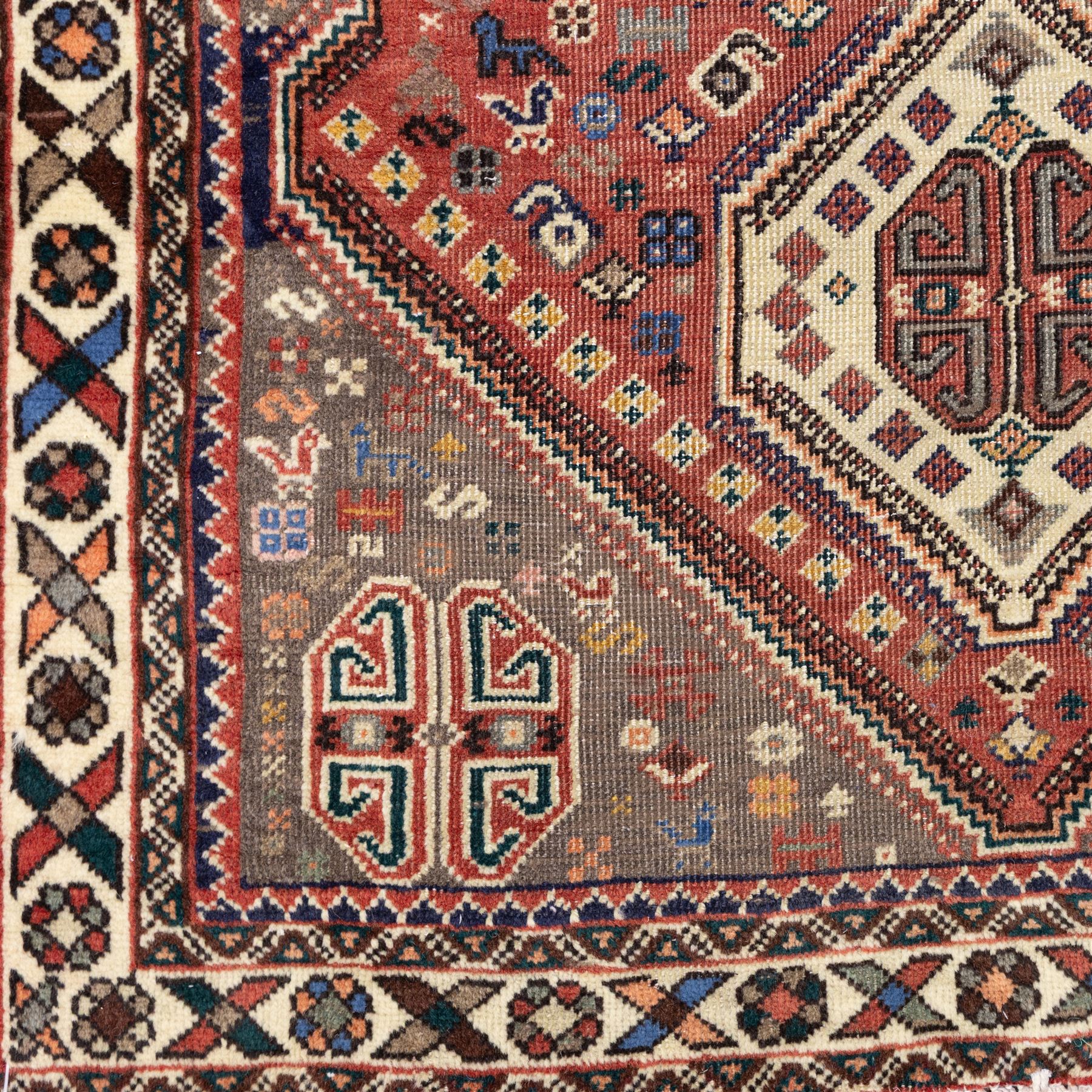South West Persian Abadeh hand-knotted runner, madder red field decorated with a vertical sequence of stepped lozenge medallions, each enclosing stylized geometric motifs and angular devices, surrounding field filled with tribal symbols and abstract forms, enclosed within a narrow main border and flanked by multiple guard stripes, with fringe ends 