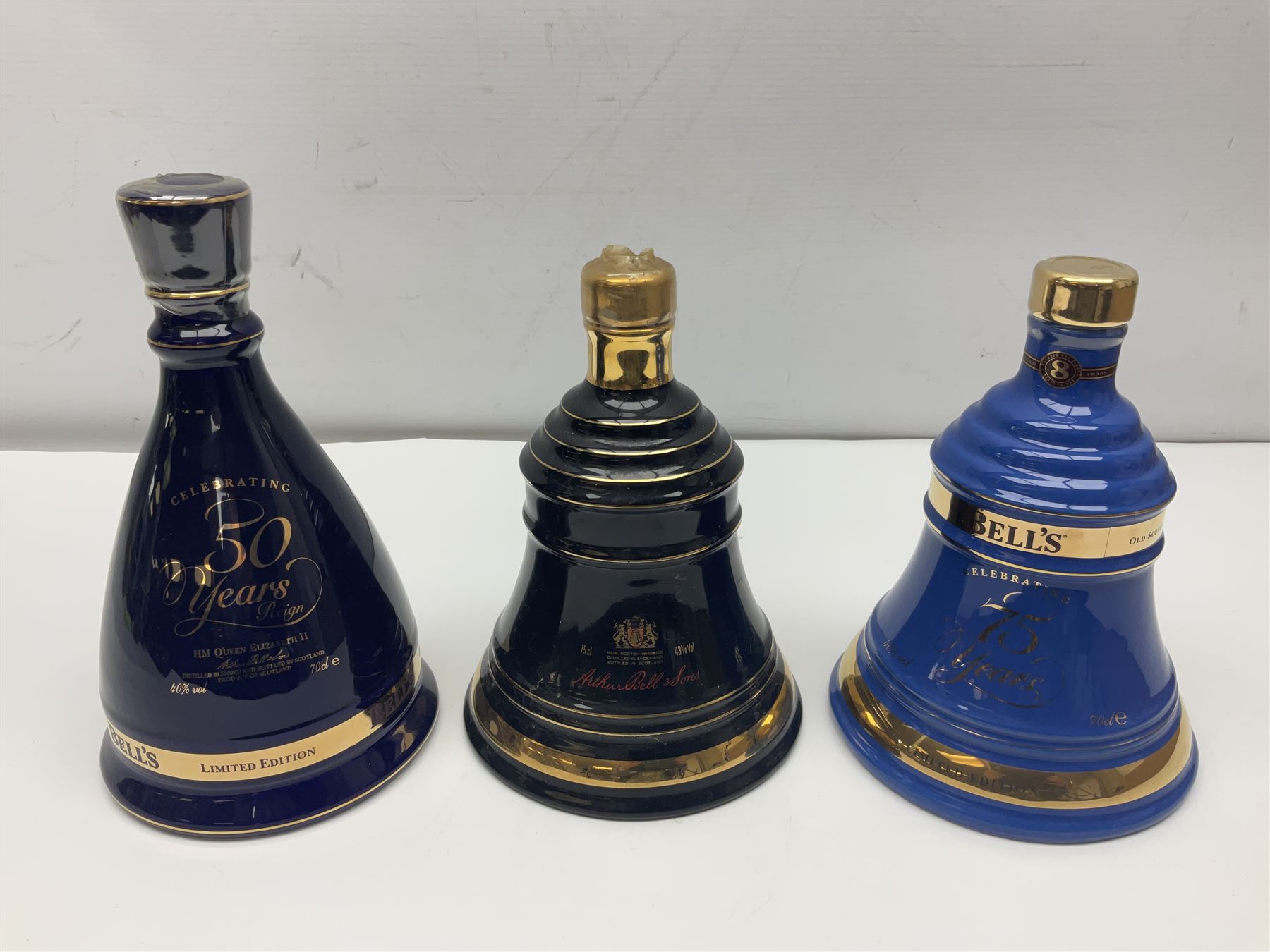 Bells, Scotch whisky, in seven Wade ceramic decanters, to include 50 year reign HM Queen Elizabeth II, Ninetieth Birthday of the Queen mother, 1991 year of the sheep, etc, together with two empty decanters and other items 