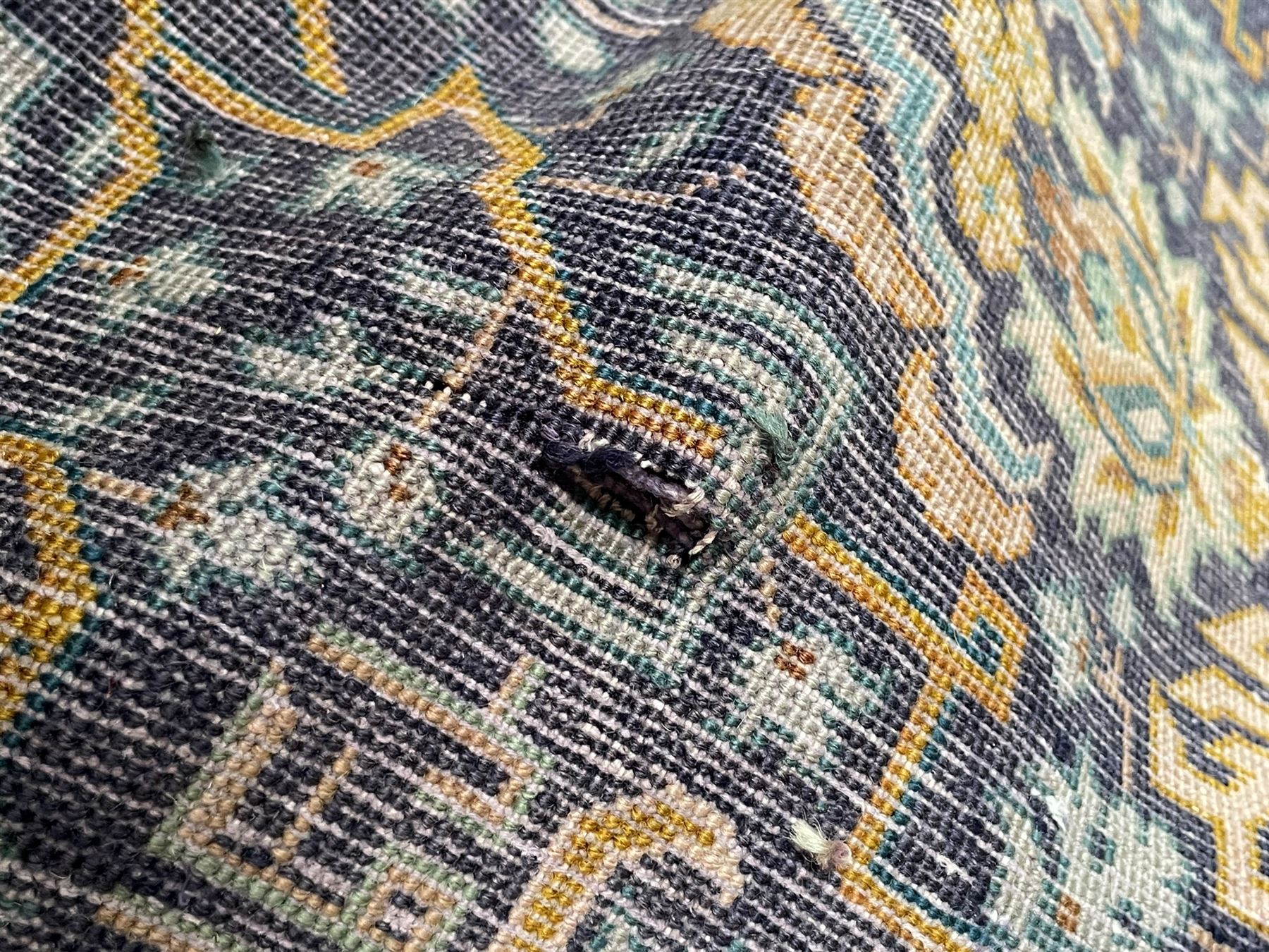 Persian indigo and pale gold ground rug, overall busy geometric design, the field decorated with hooked Hac and palmette medallions surrounded by densely patterned zig-zags and stylised foliate motifs, the border decorated with smaller Hac motifs, within multiple guard stripes 