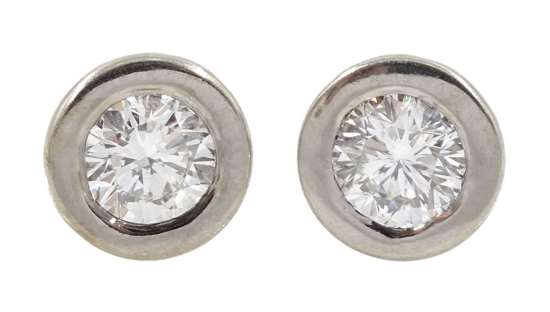 Pair of 18ct white and yellow gold round brilliant cut diamond stud earrings, rubbover set, stamped 750, total diamond weight 0.62 carat