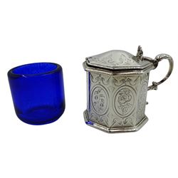 Victorian silver mustard pot, of octagonal form with bright cut engraved decoration and scroll handle, the slightly domed cover with scroll decorated thumbpiece lifting to reveal a later blue glass liner, hallmarked Henry Holland, London 1855, H7.5cm, approximate weight excluding liner 5.33 ozt (166 grams)