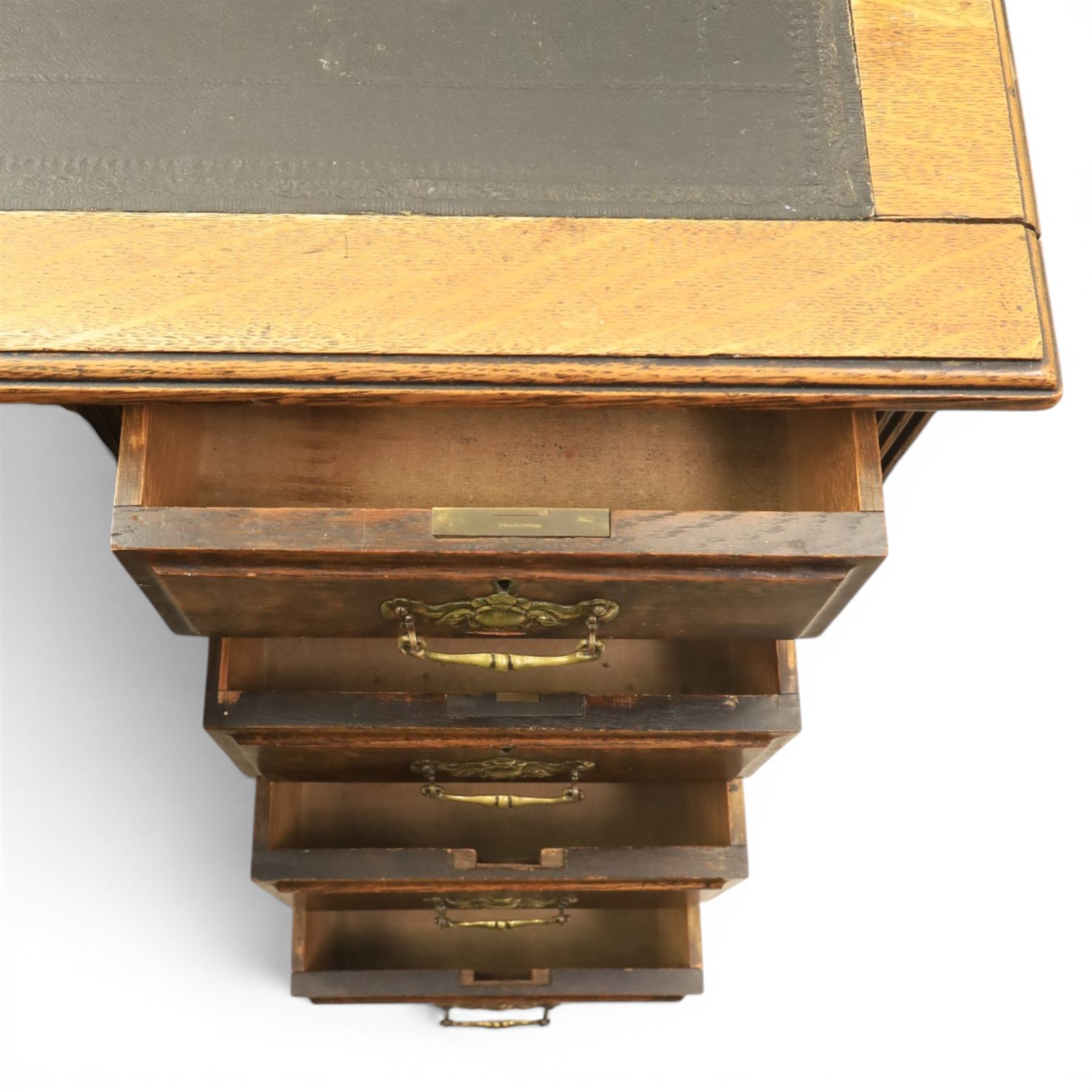 Oak twin pedestal desk with leather top, moulded rectangular top with inset black leather writing surface, nine fielded panelled drawers with brass handles, raised on a plinth base with castors