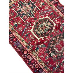 Persian Karajeh red ground runner, the field set with nine trailing geometric medallions, decorated all over with stylised motifs, geometric design with multiple banded border