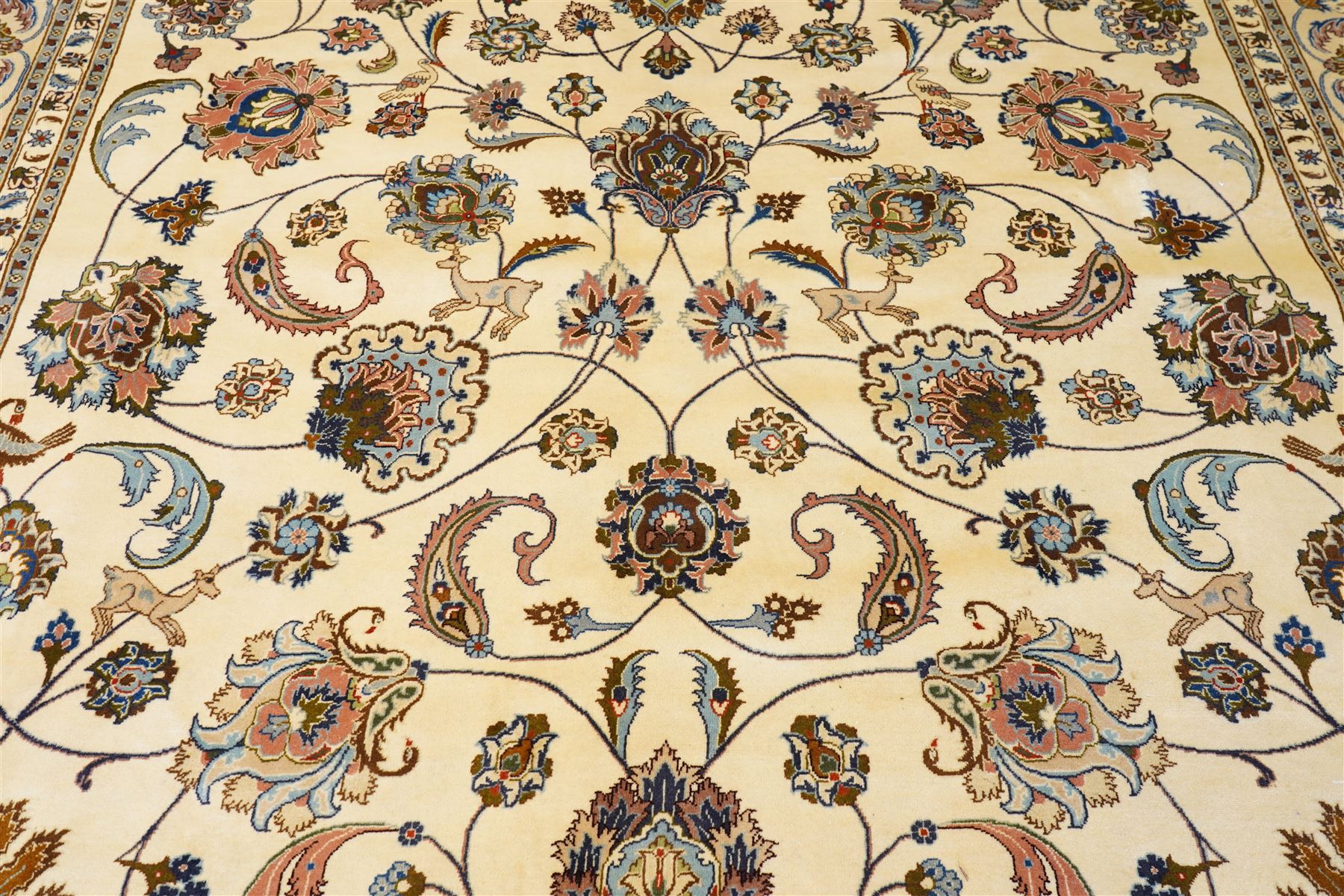 North East Persian Mashad hand-knotted carpet, ivory field decorated with an all-over scrolling floral vine design incorporating stylized palmettes, deer, rosettes and floral sprays enclosed by a conforming floral vine border between multiple guard stripes, cotton fringe ends