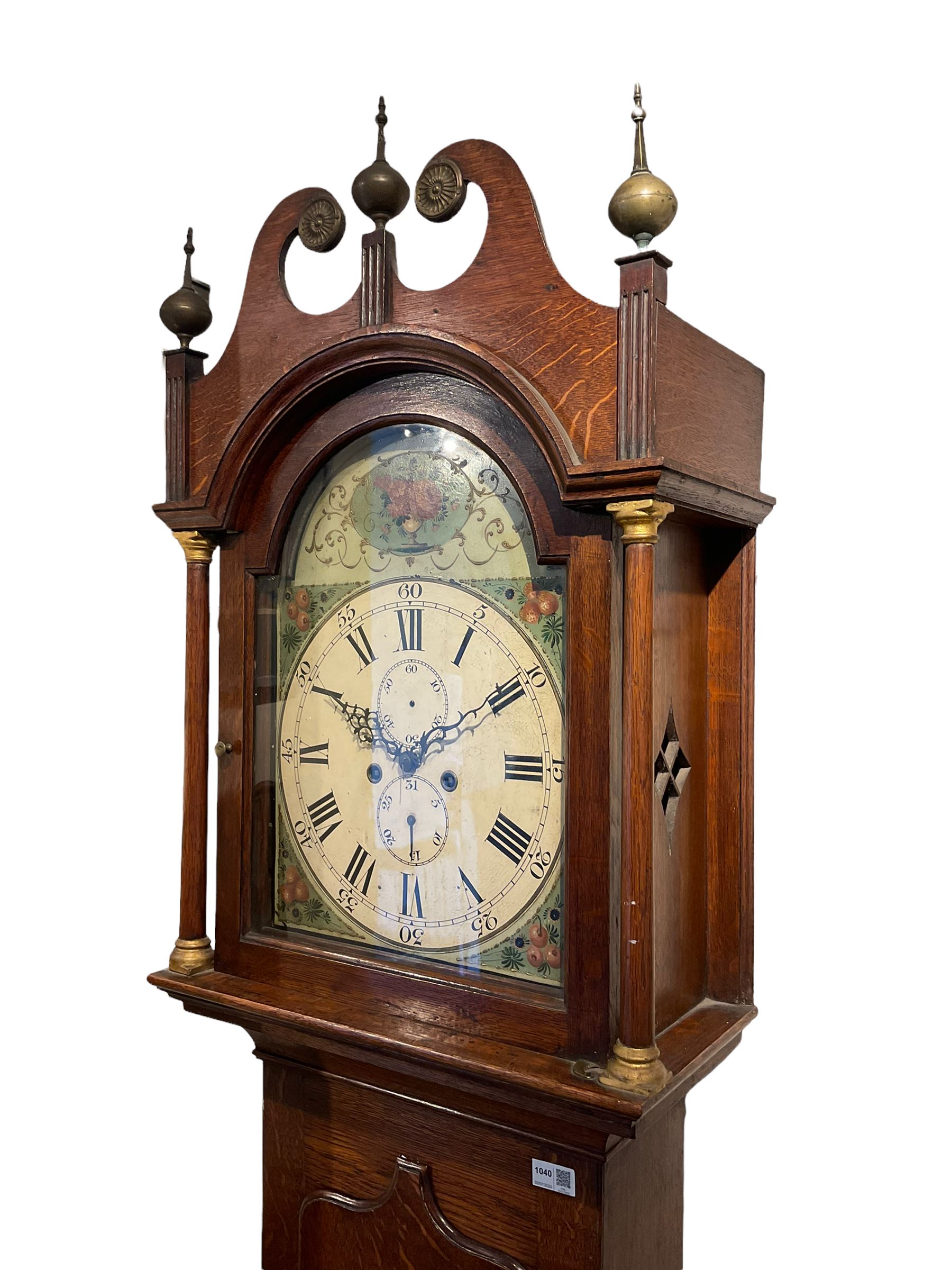 English oak cased longcase clock c1830, tall swan neck pediment with three ball and spire finals and brass paterae, break arch hood door flanked by two tapered columns with gesso capitals, with a slim trunk and full length door with a decorative ogee spire, on a square plinth with applied skirting, painted break-arch dial with depictions of flowers to the spandrels and break arch, spandrels and arch with raised gesso detailing on a green background, dial with Roman numerals and five-minute Arabic's, minute track, subsidiary date and seconds dial, with steel hands and calendar pointer (no second's hand), dial pinned via a cast falseplate to an eight-day rack striking movement, striking the hours on a bell. With weights,  pendulum and key.

