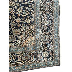 Persian Kashan indigo ground rug, the rosette medallion decorated with projecting palmettes, on a field of swirling leafy branches and decorated with further palmettes, the scrolling border with repeating stylised plant motifs, within floral pattern guard stripes