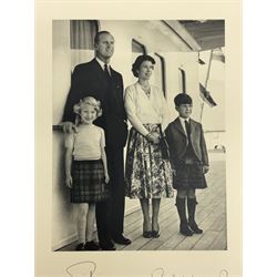 HM Queen Elizabeth II and HRH The Duke of Edinburgh - signed 1956 Christmas card with gilt embossed crown to cover, black and white photograph of the smiling Royal Couple with Prince Charles and Princess Anne on board Britannia, signed in ink 'Philip 1956 Elizabeth R',