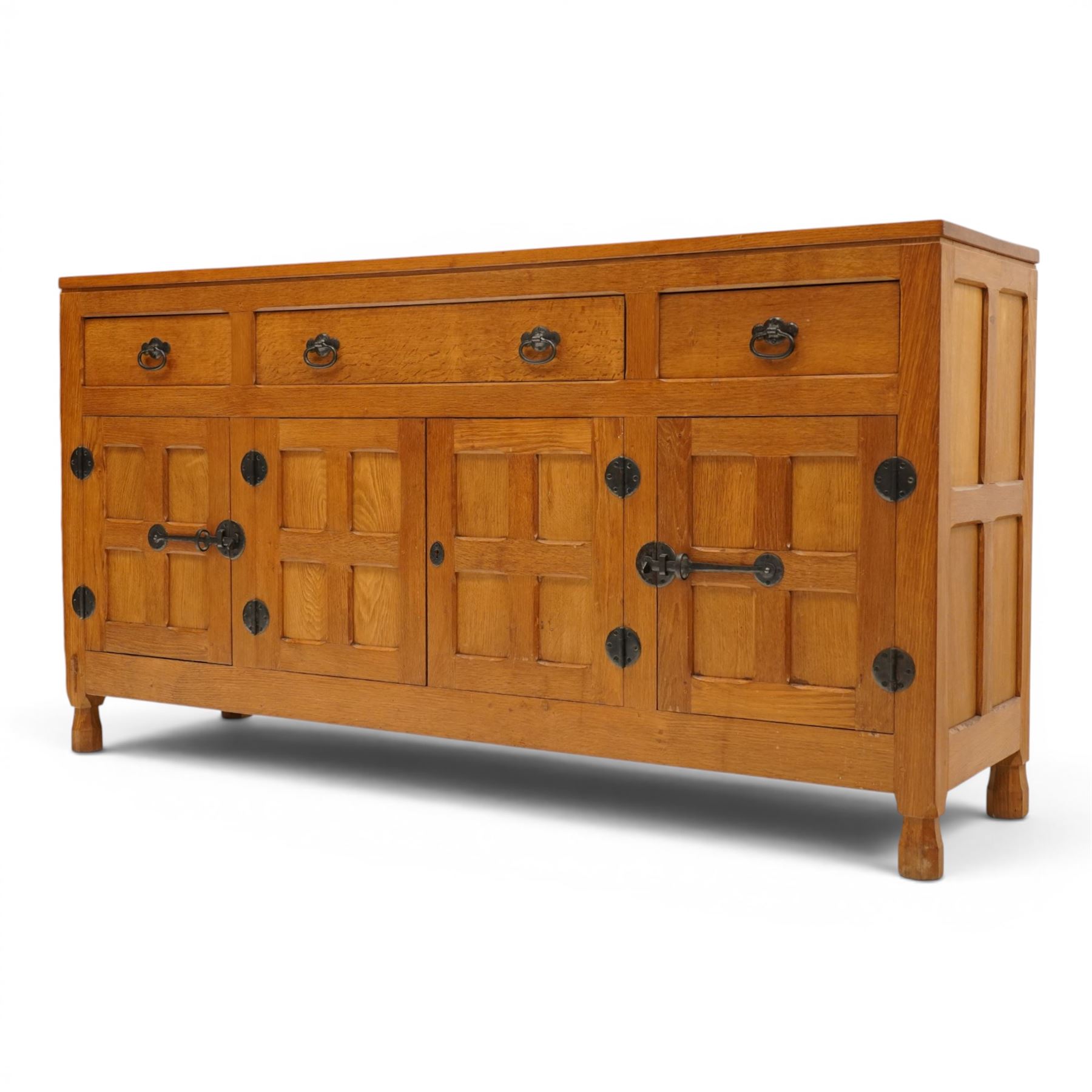 Lizardman - oak 5' sideboard, rectangular top over three panelled frieze drawers, fitted with two double panelled cupboards with wrought iron handles and locks, raised on tapered octagonal feet, with carved lizard signature, by Derek Slater of Crayke
